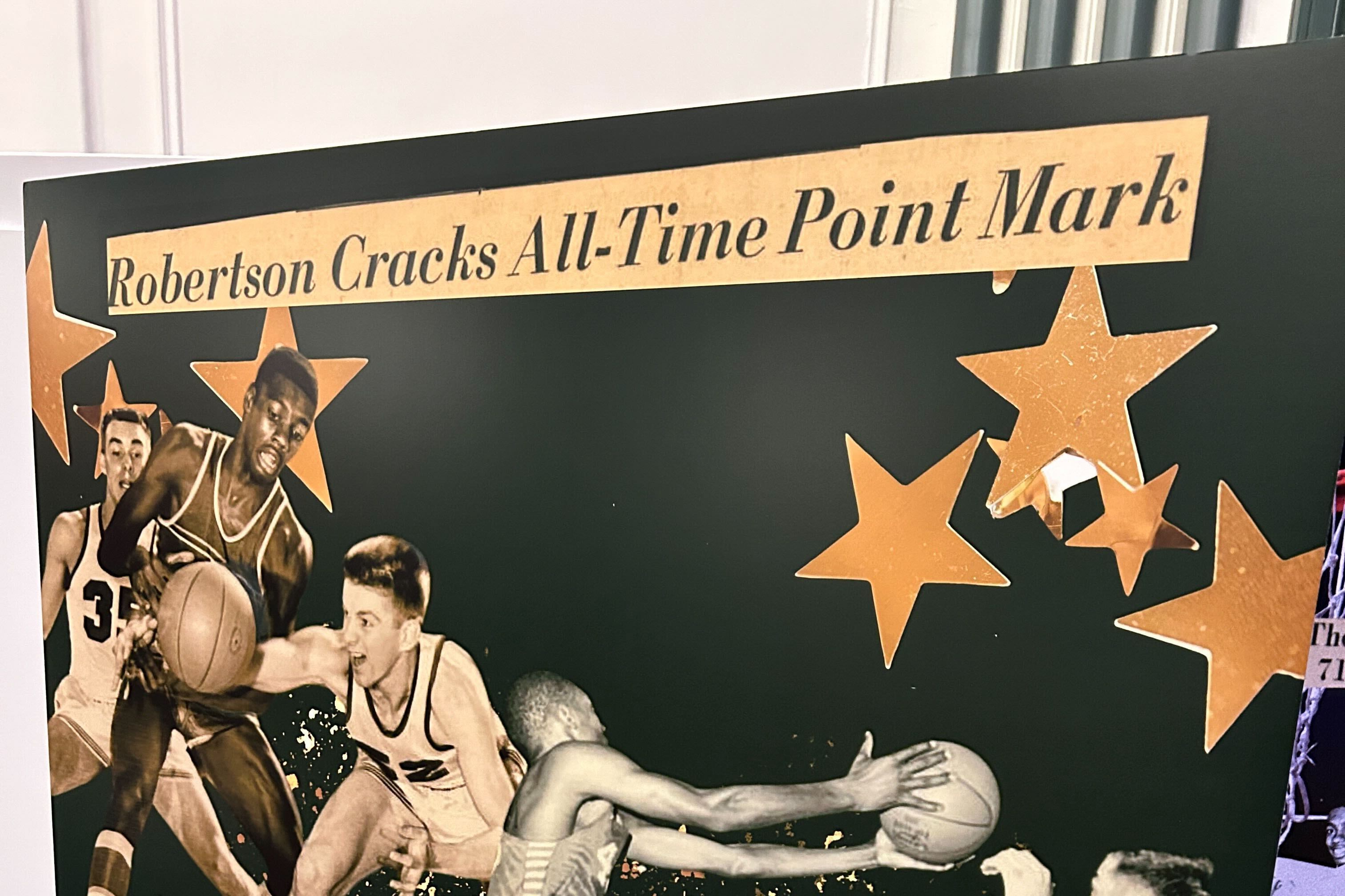 A collage of black and white photos of basketball players with gold stars and newspaper print at the top that reads "Robertson Cracks All-Time Point Mark."
