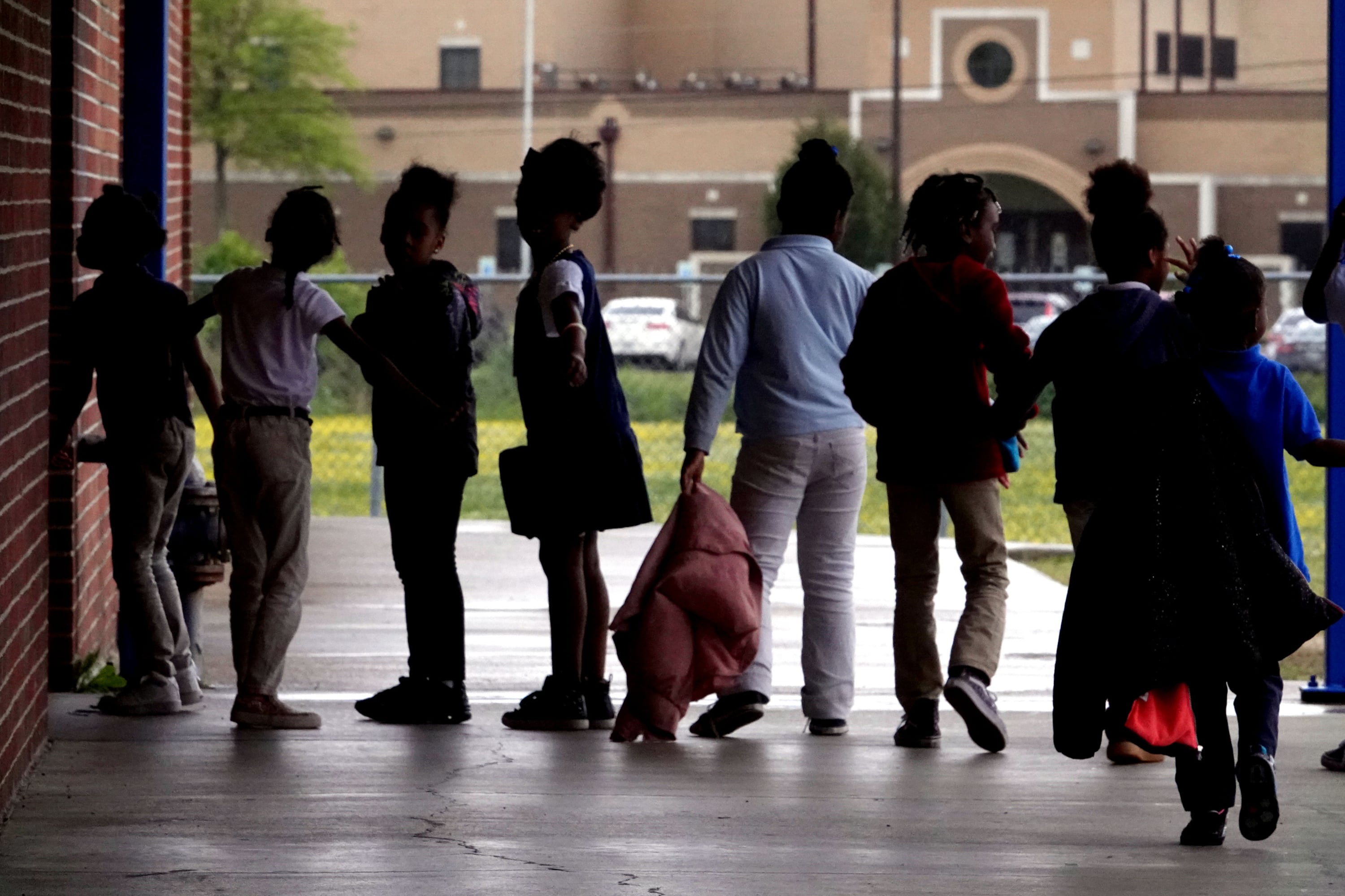 Young students line up outside of a school building.