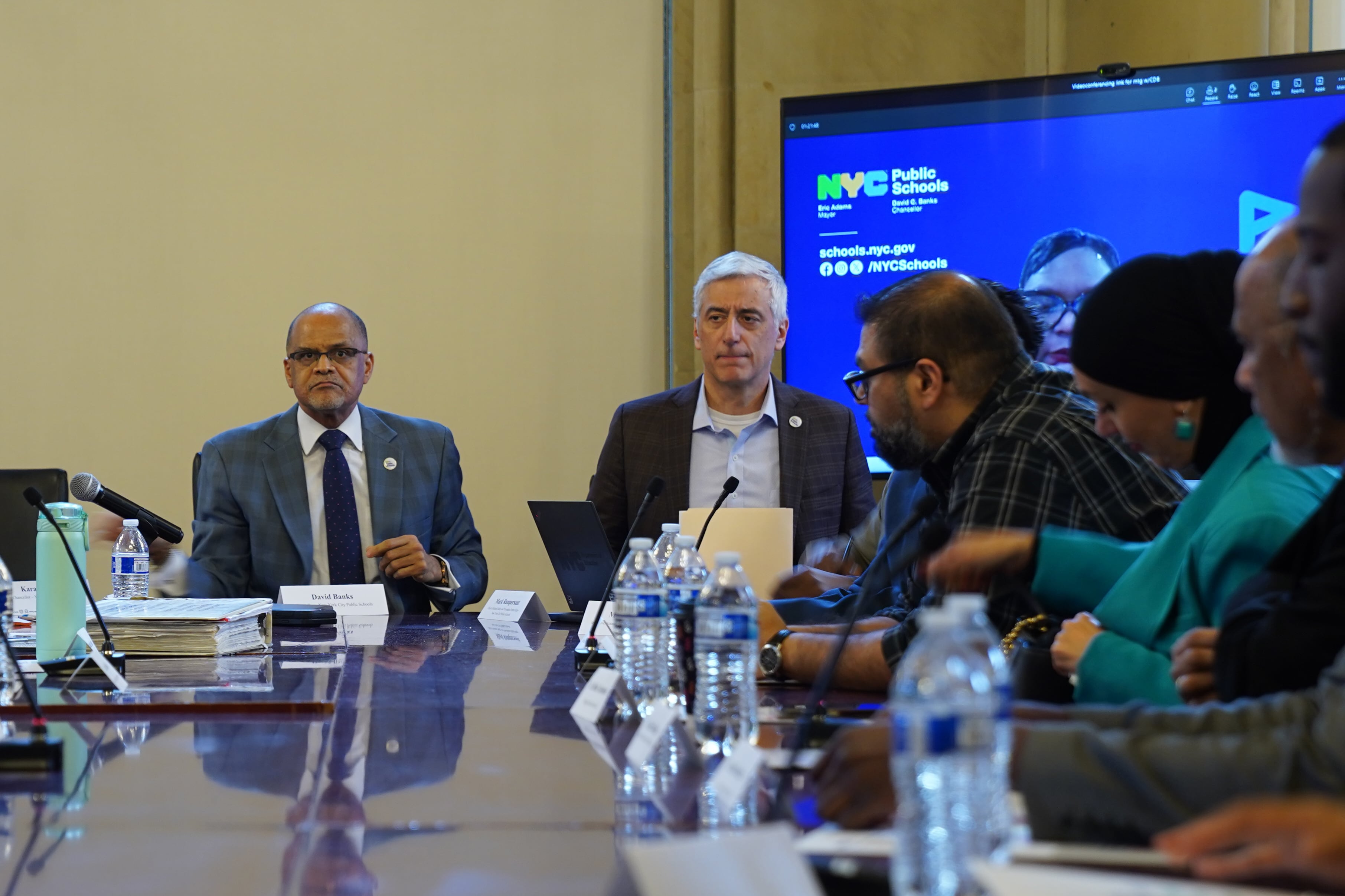 A group of people sit around a table in a meeting.