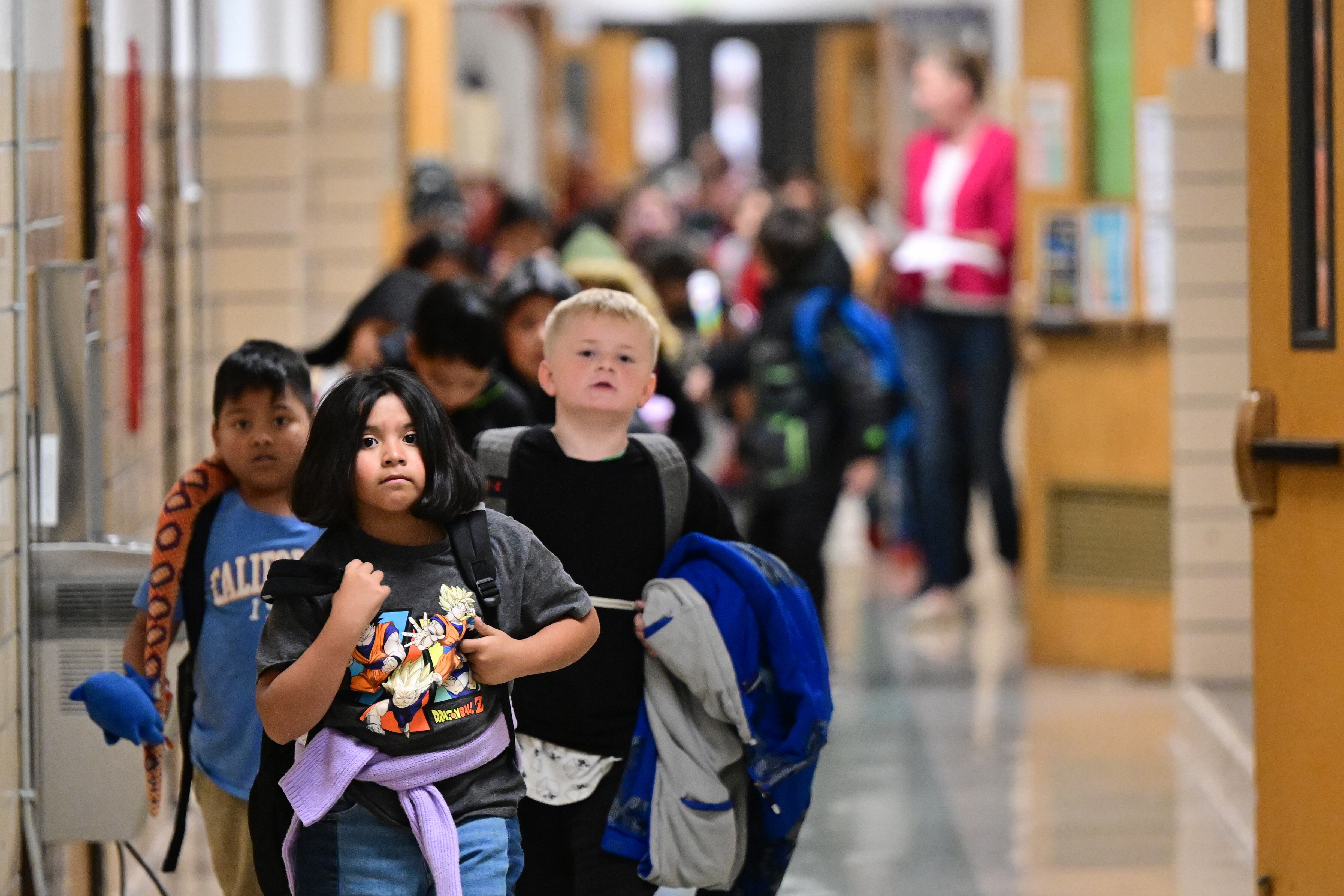 Young students walk through an elementary school hallway.