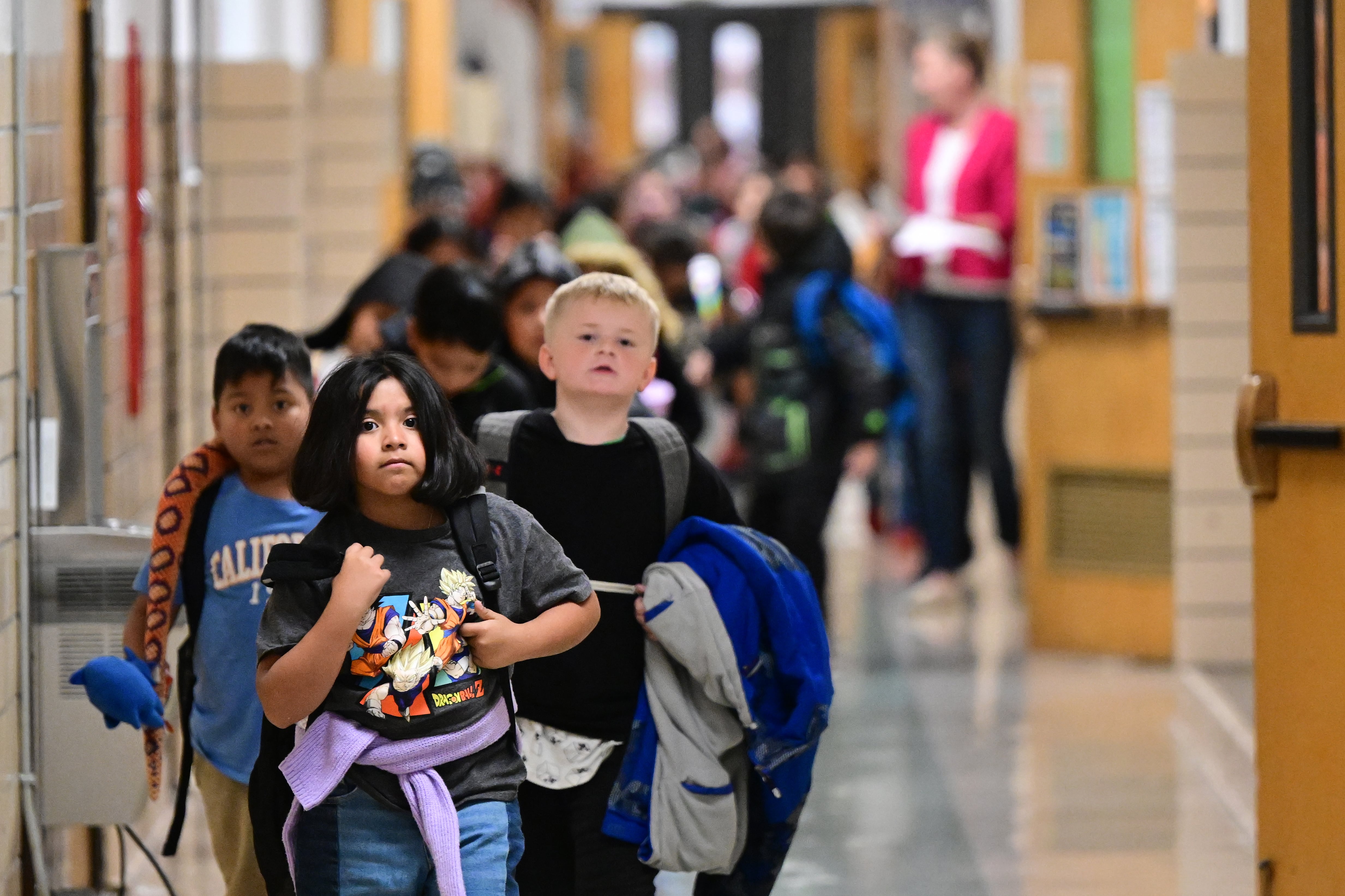 Young students walk through an elementary school hallway.