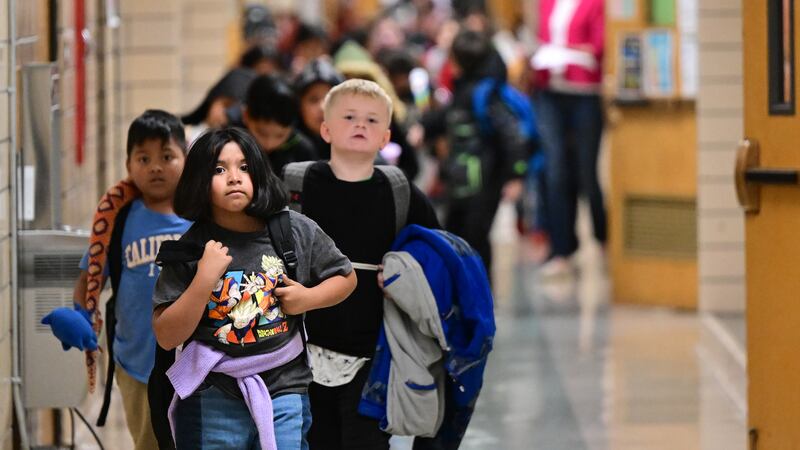 Young students walk through an elementary school hallway.