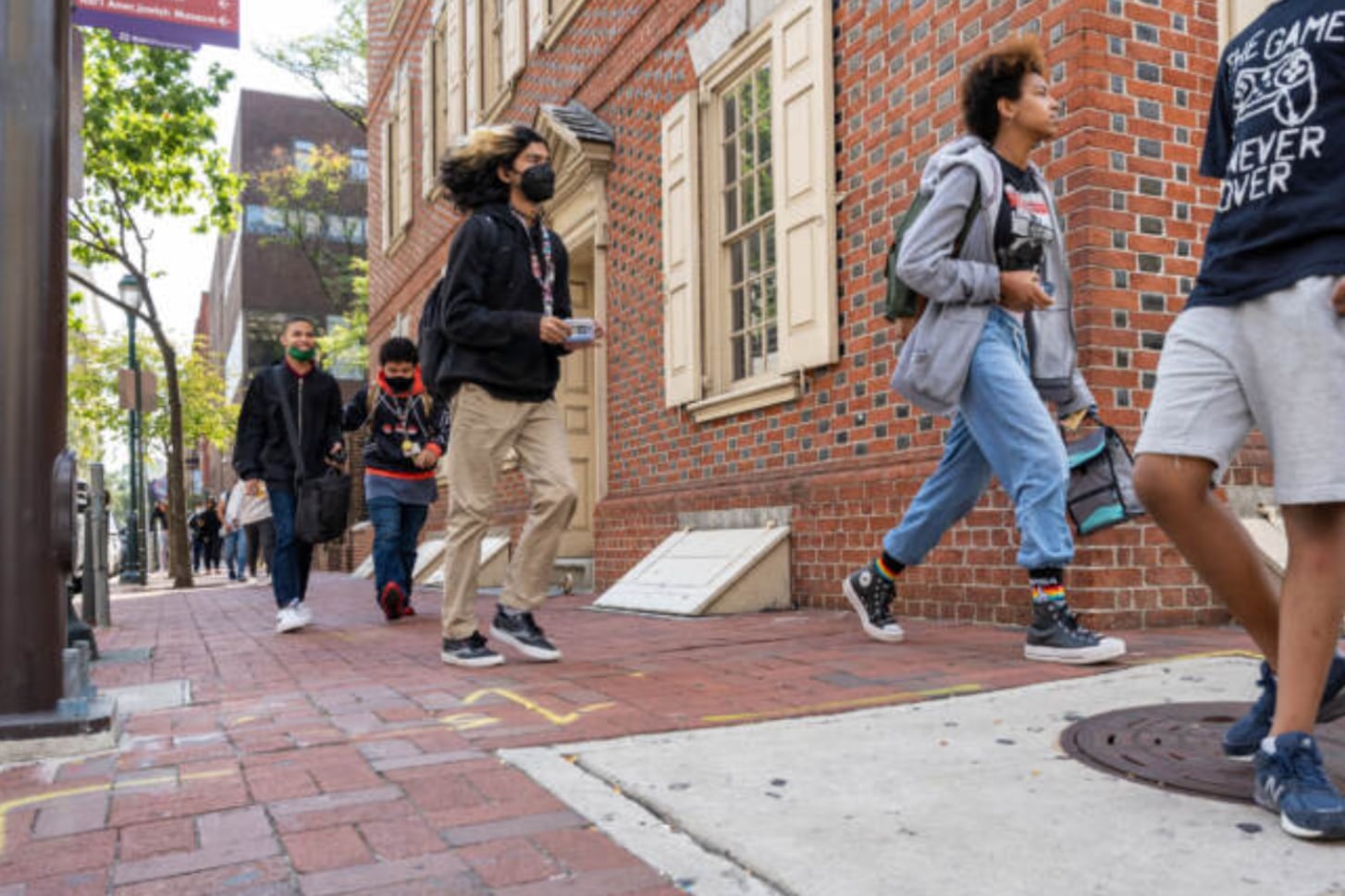 Students wearing backpacks walk in front of a brick building.