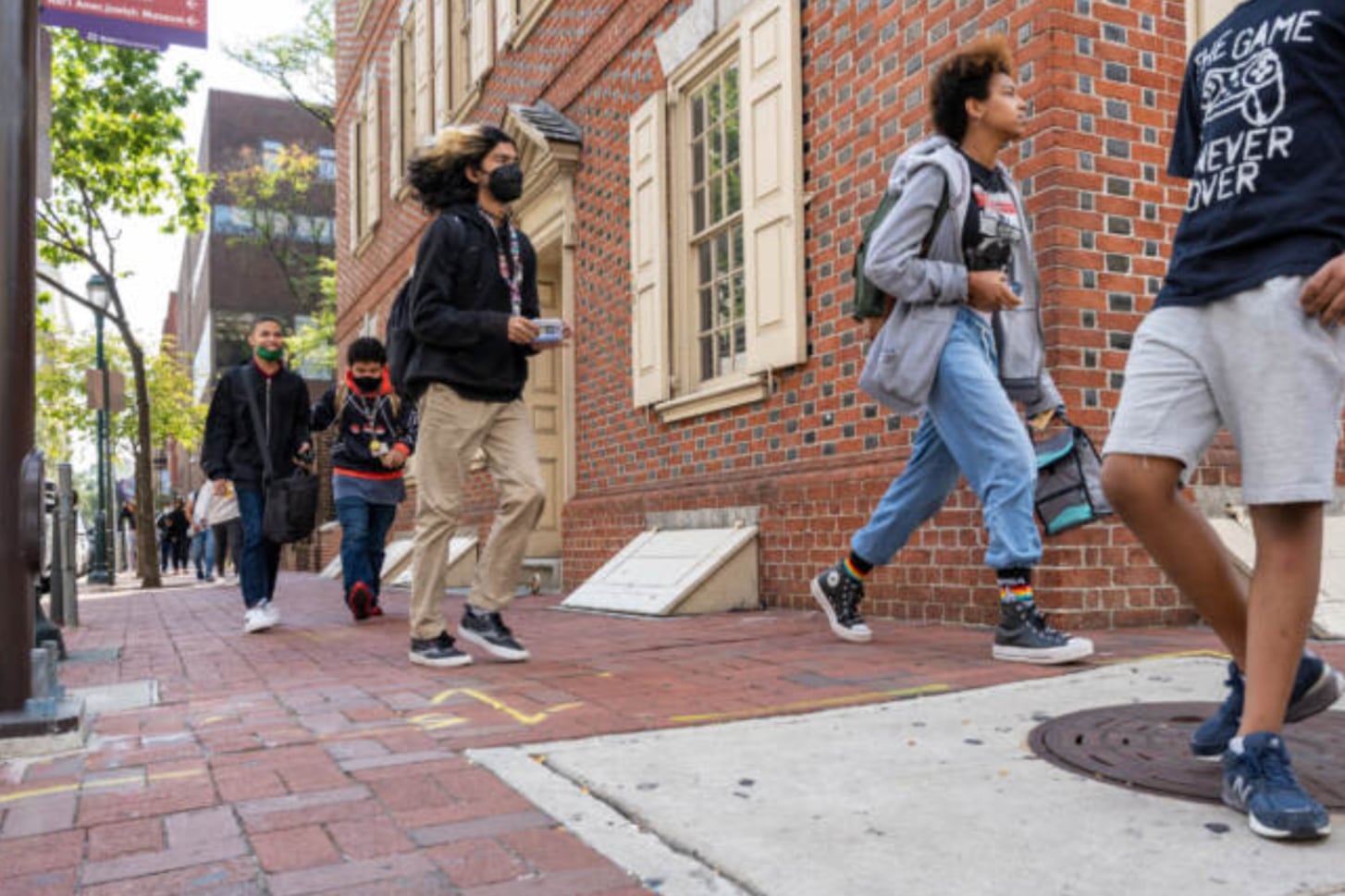 Students wearing backpacks walk in front of a brick building.