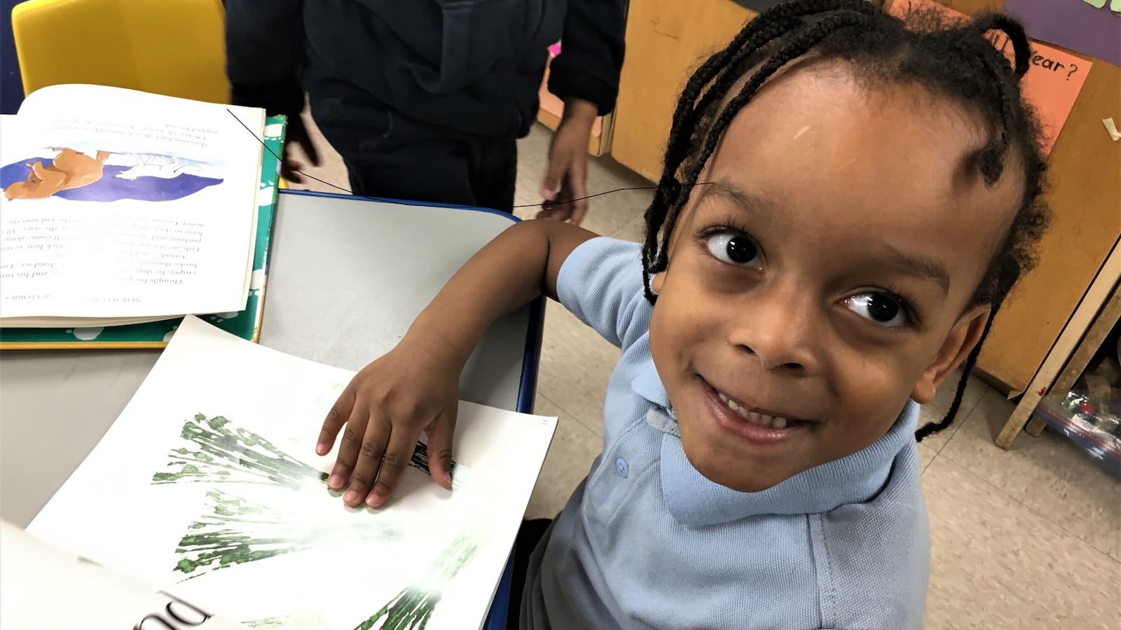 A pre-school student looks up from her reading.