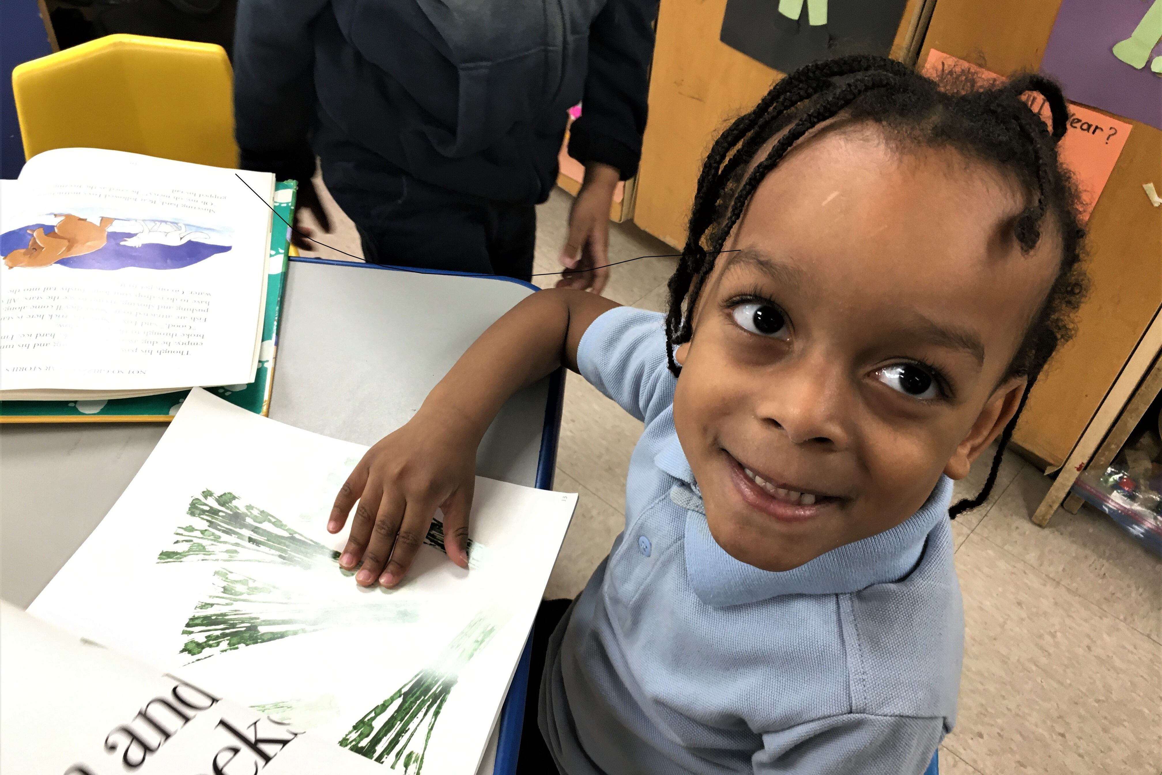A pre-school student looks up from her reading.