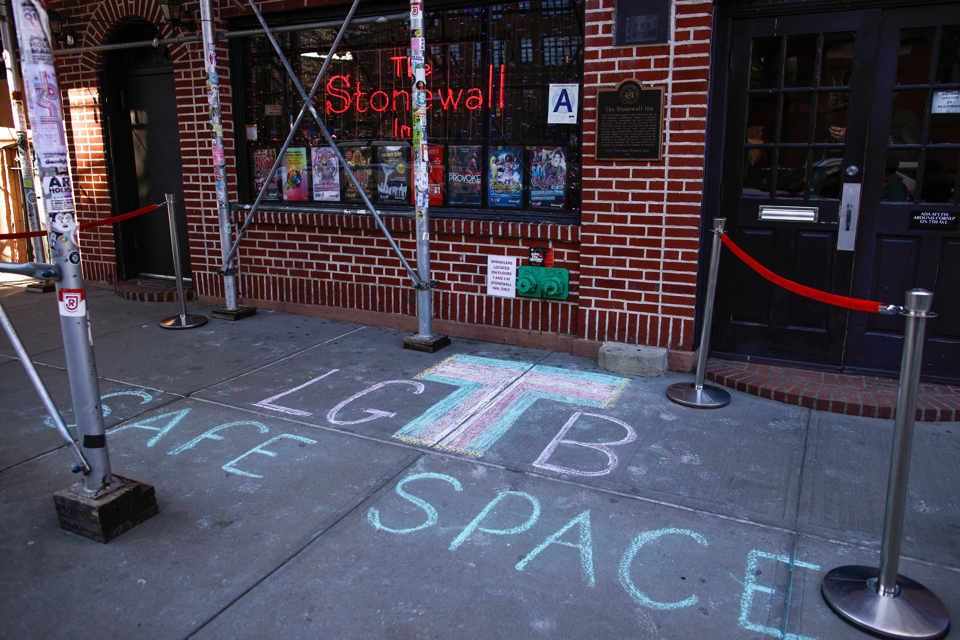 The front entrance to The Stonewall Inn and a sidewalk with chalk writing that reads "LGTB Safe Space."