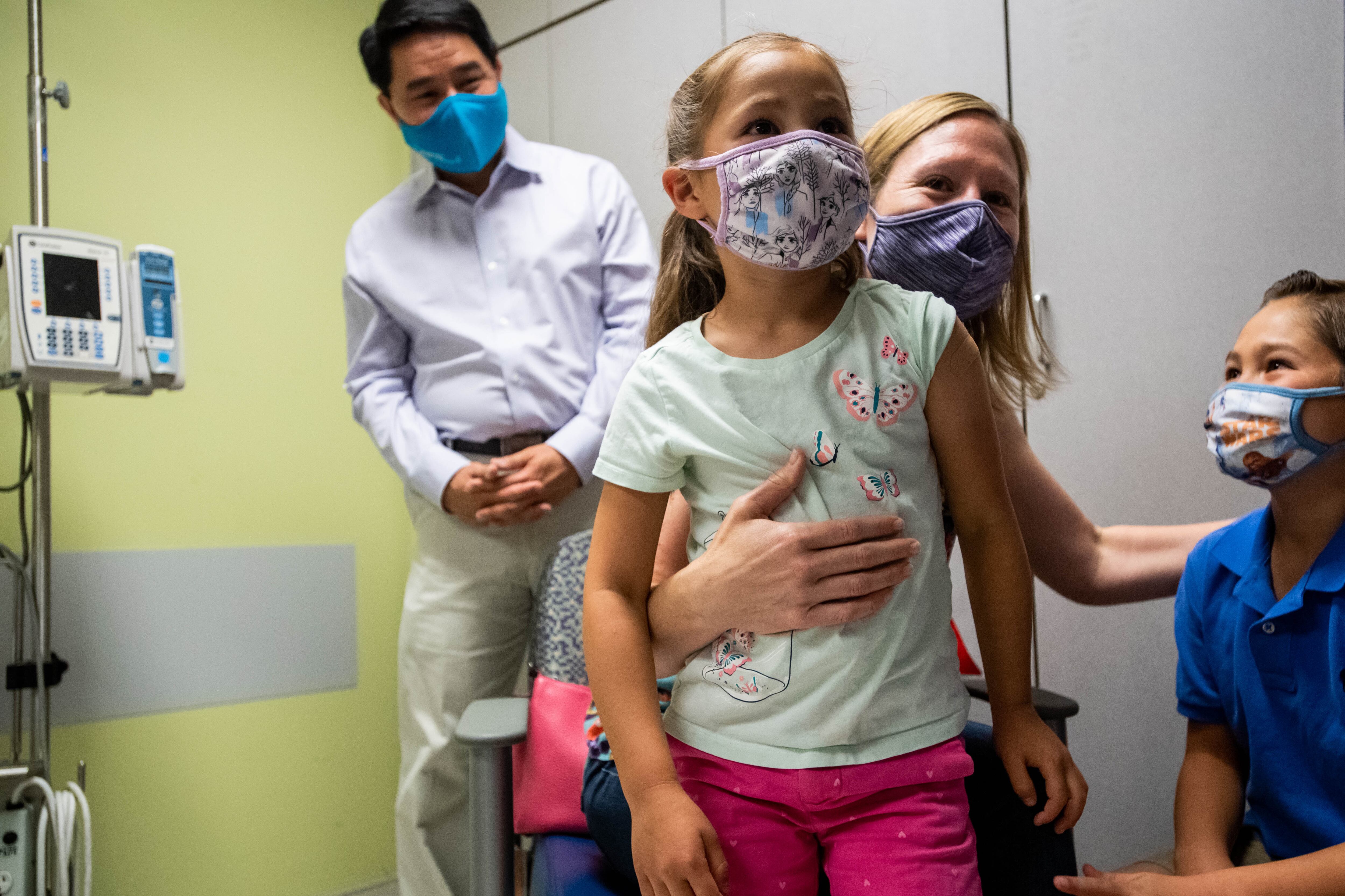 A family embraces after their two daughters receive the COVID vaccine during a trial for children.