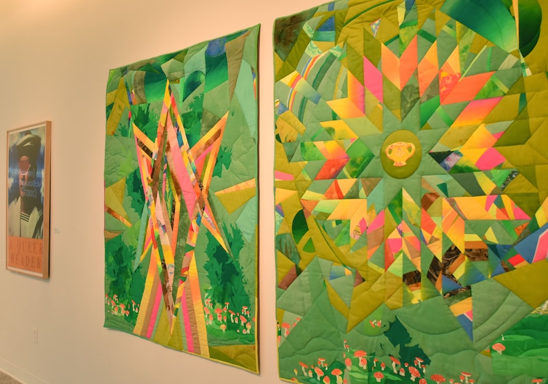 Two large colorful pieces of art hang on a blank wall next to a smaller piece of art.