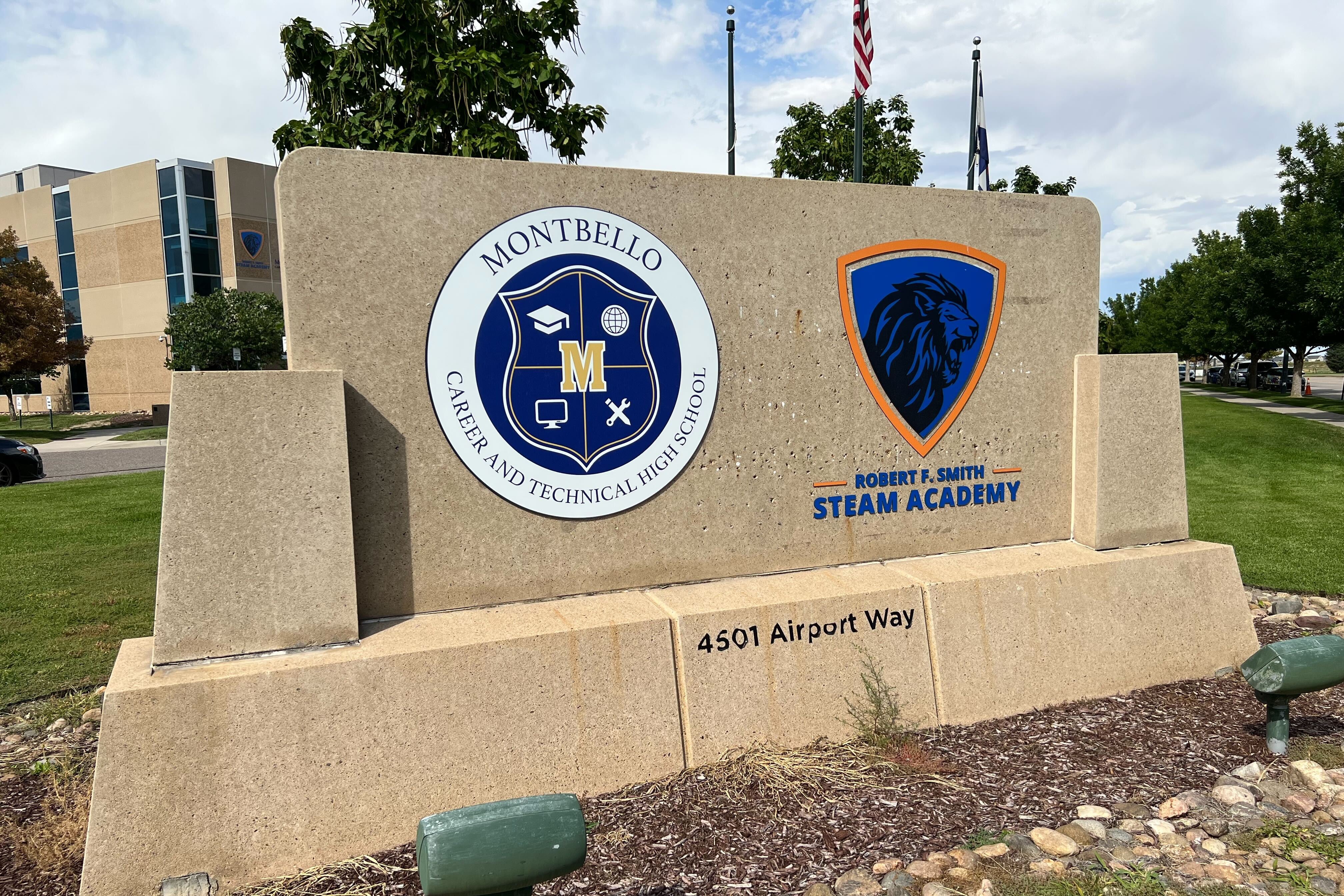A stone sign with the logos of two high schools on it.