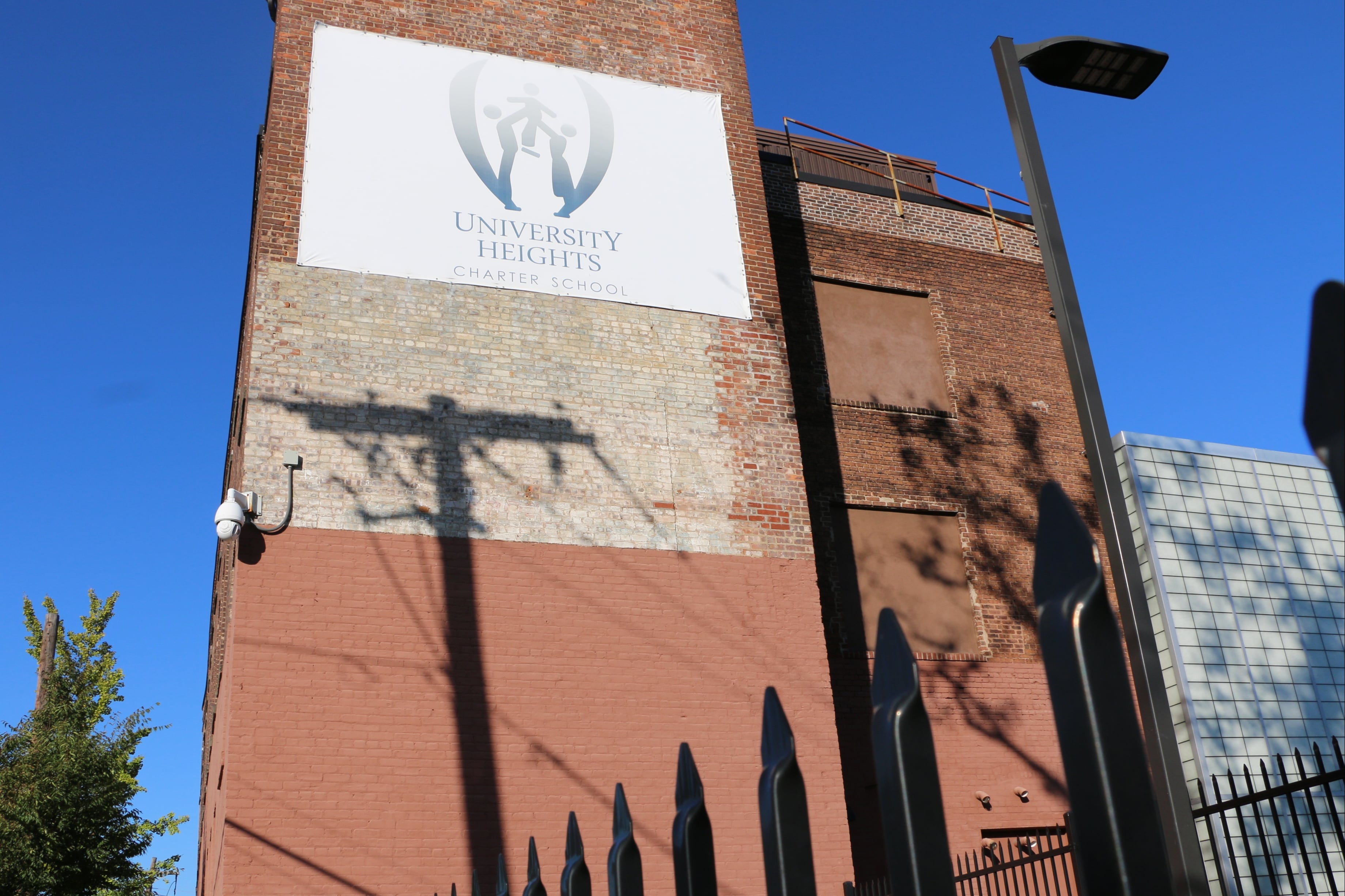 Light posts cast shadows on the brick facade of University Heights Charter School in Newark.