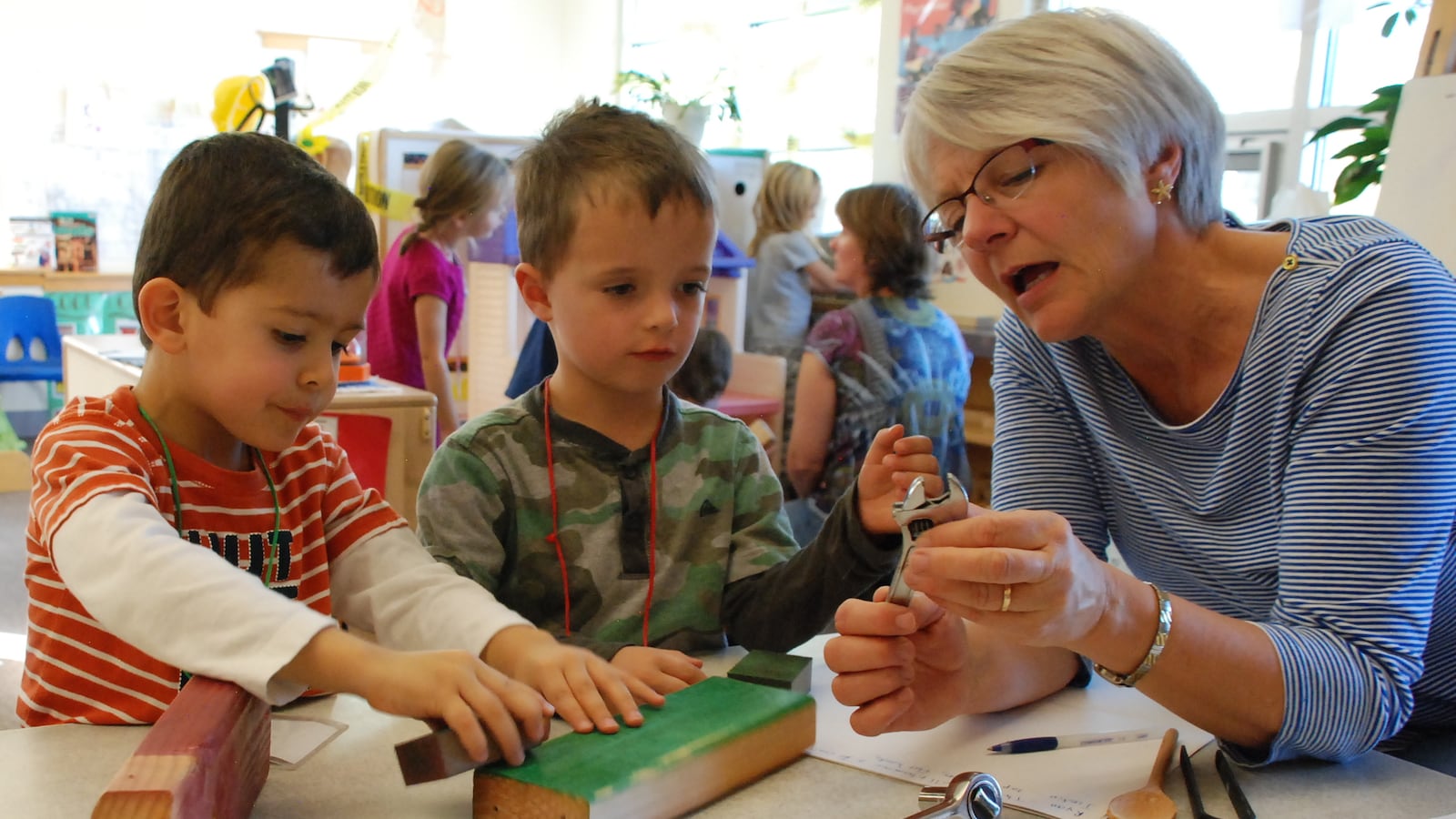 Teacher Dee Gilmore talks with two preschoolers at the Bal Swan Children's Center about tools.