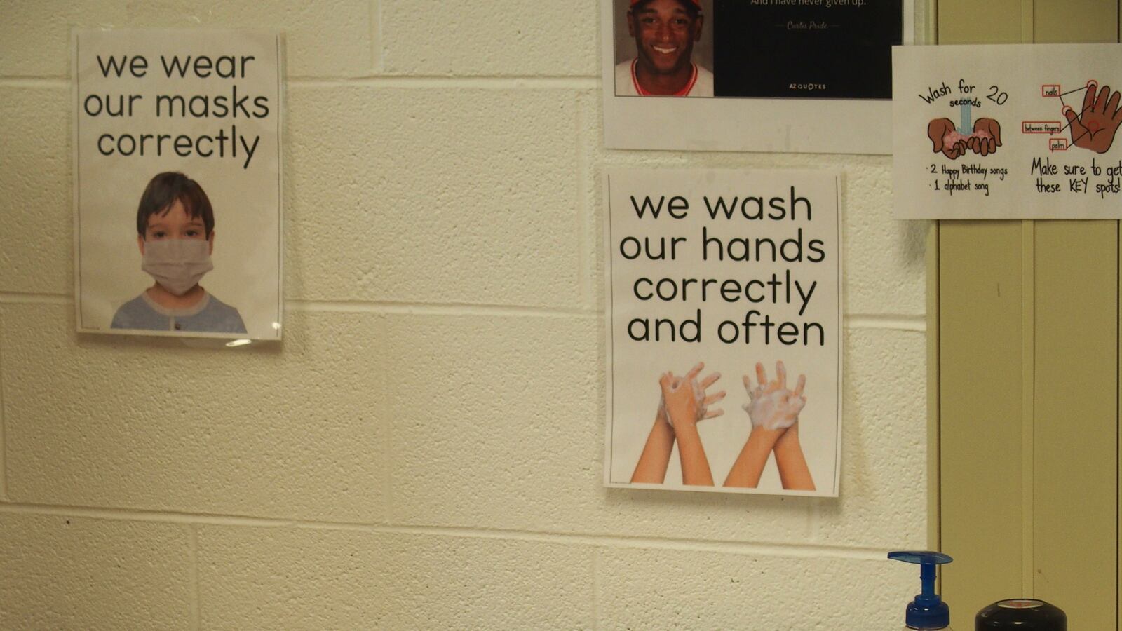 Signs at a classroom sink urging students to wash their hands and wear their masks correctly.