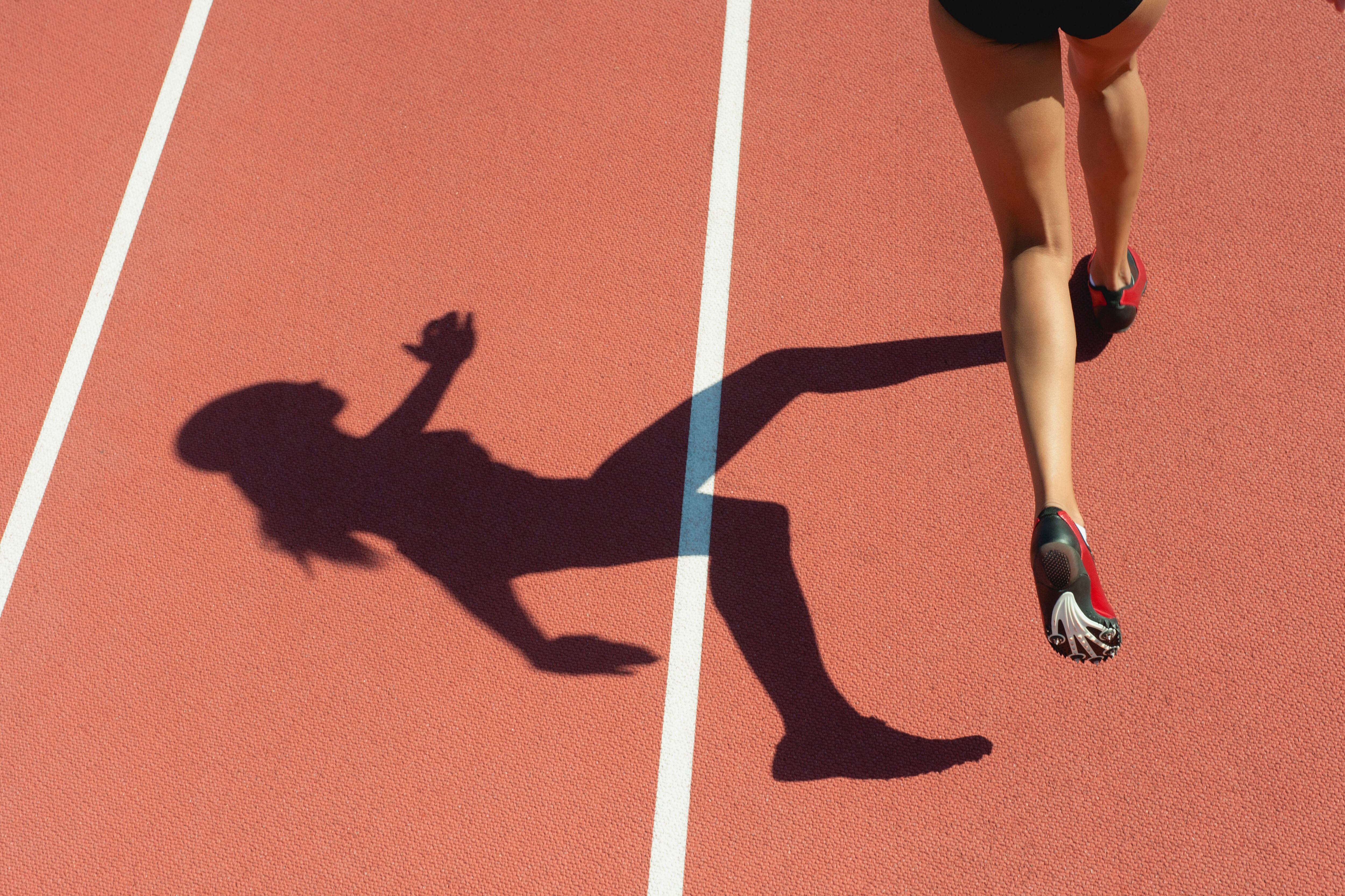 A female runner casts a shadow on a track.