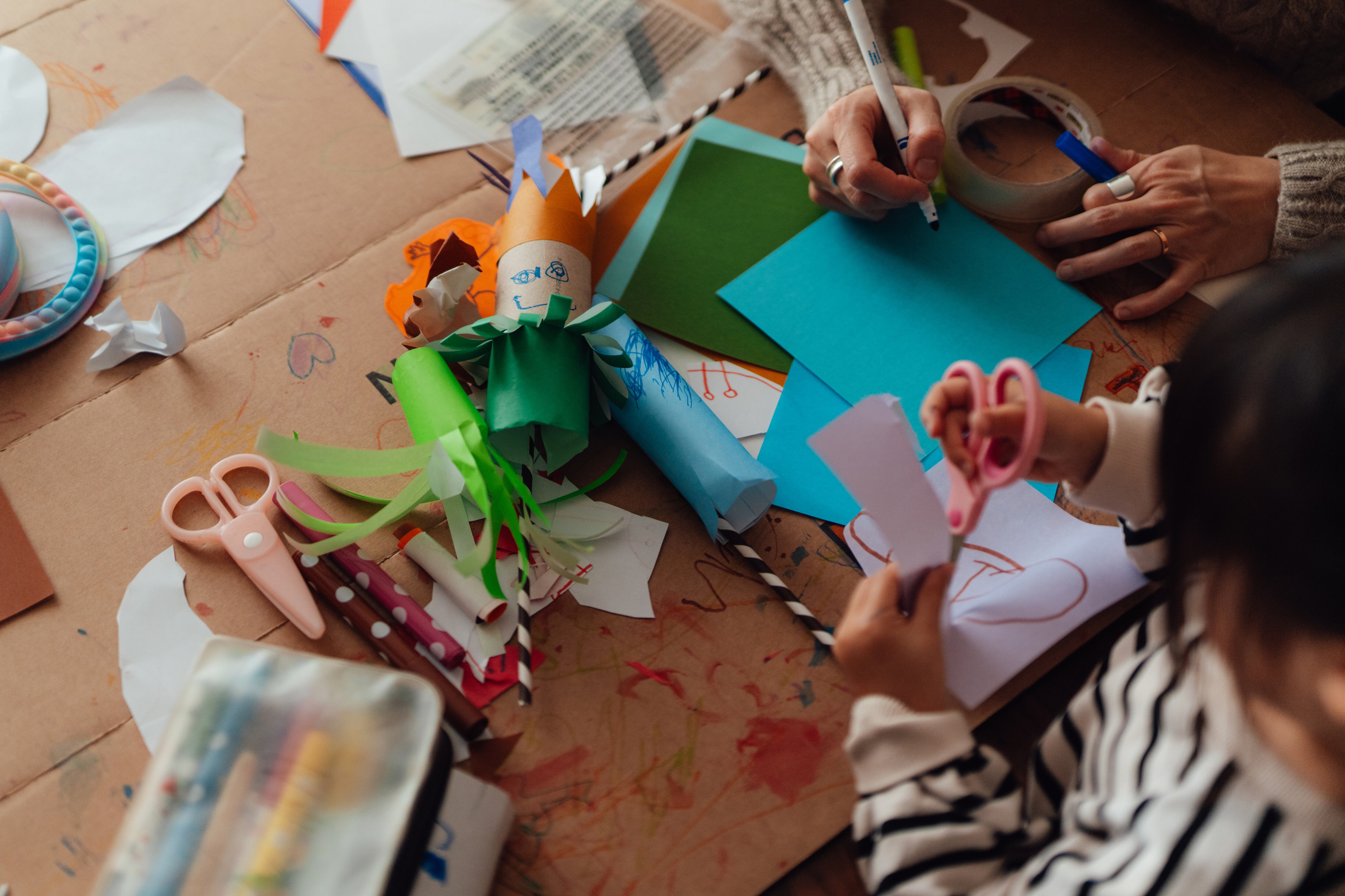 A child and a woman work on an art project at a table.