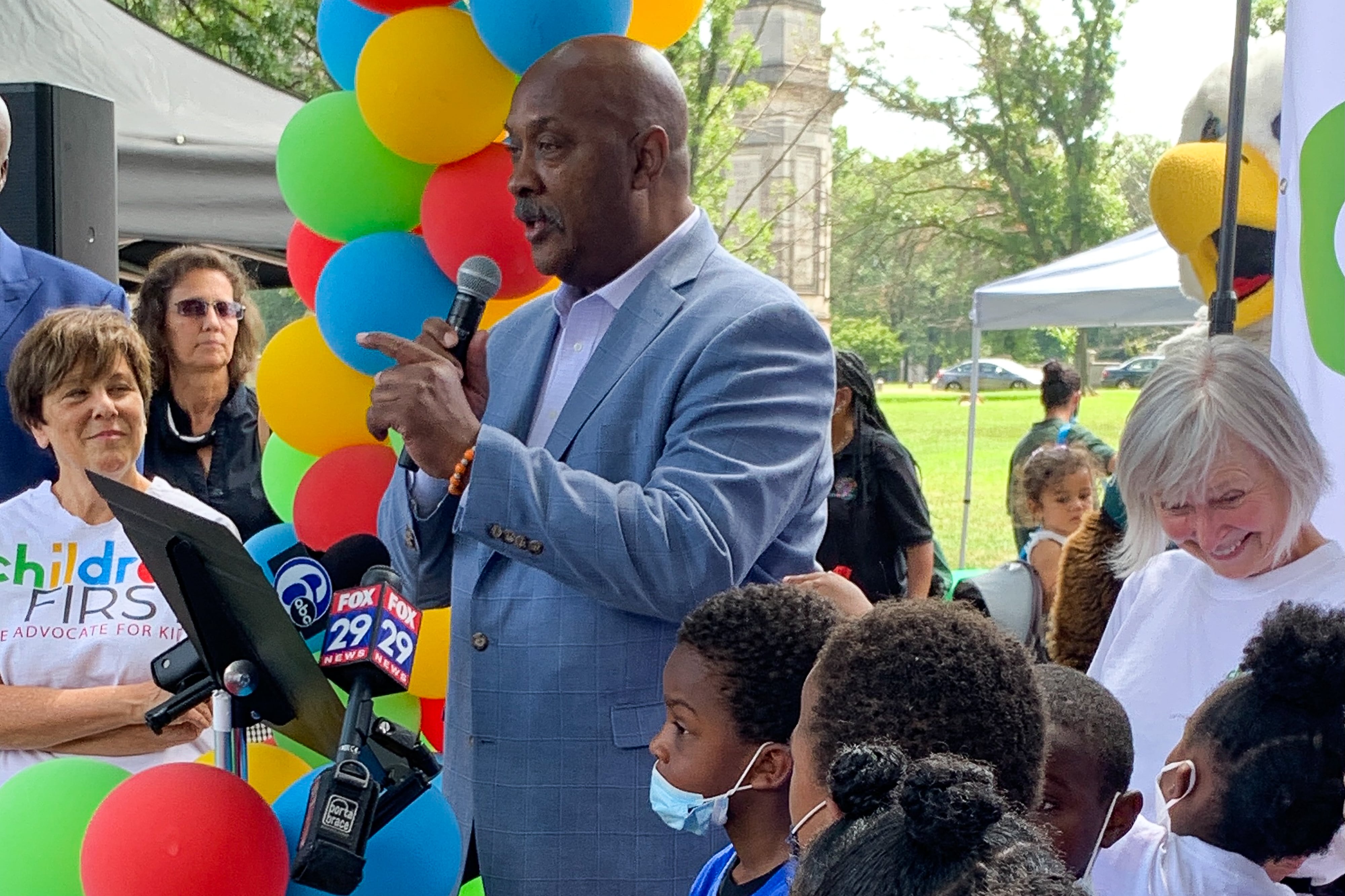 U.S. Rep. Dwight Evans speaks at Children First event Thursday. The organization’s executive director, Donna Cooper, is to his left wearing the Children First T-shirt, and there are several children and a few other adults around him.