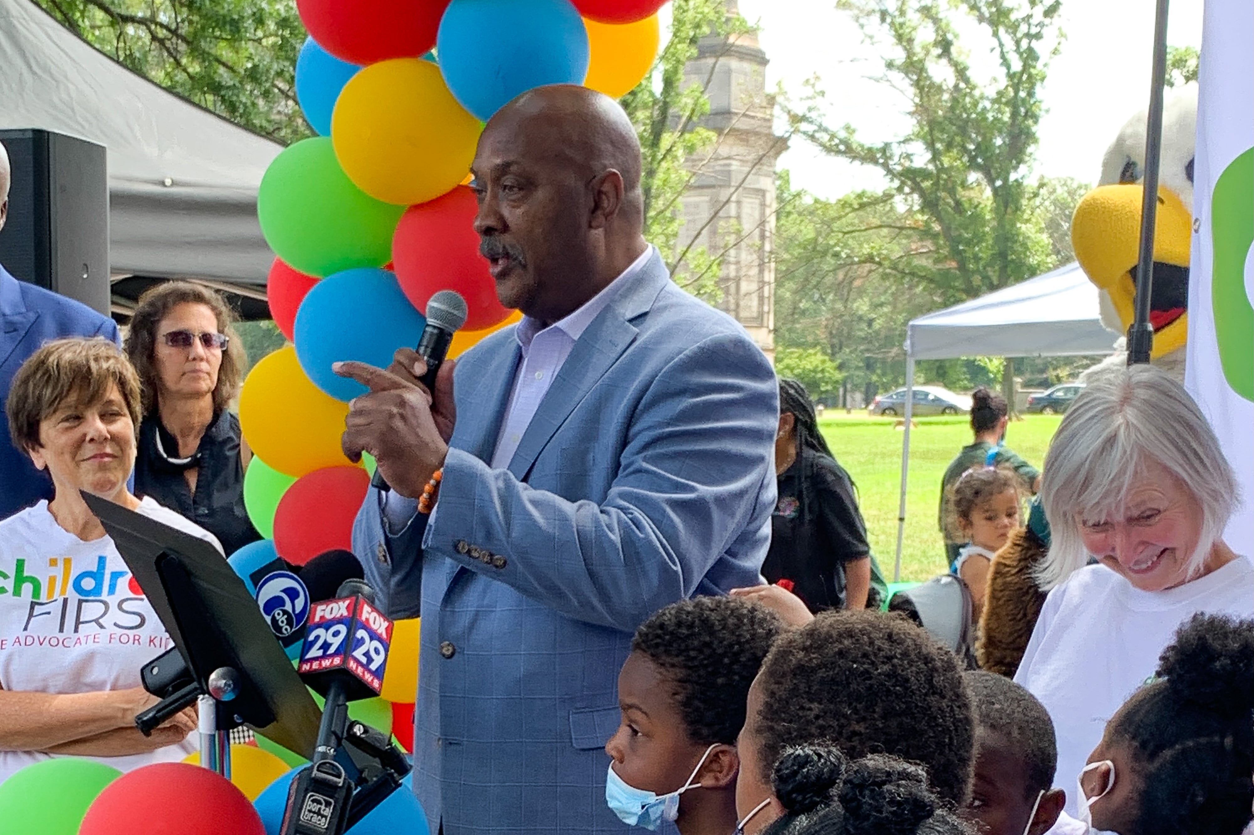 U.S. Rep. Dwight Evans speaks at Children First event Thursday. The organization’s executive director, Donna Cooper, is to his left wearing the Children First T-shirt, and there are several children and a few other adults around him.