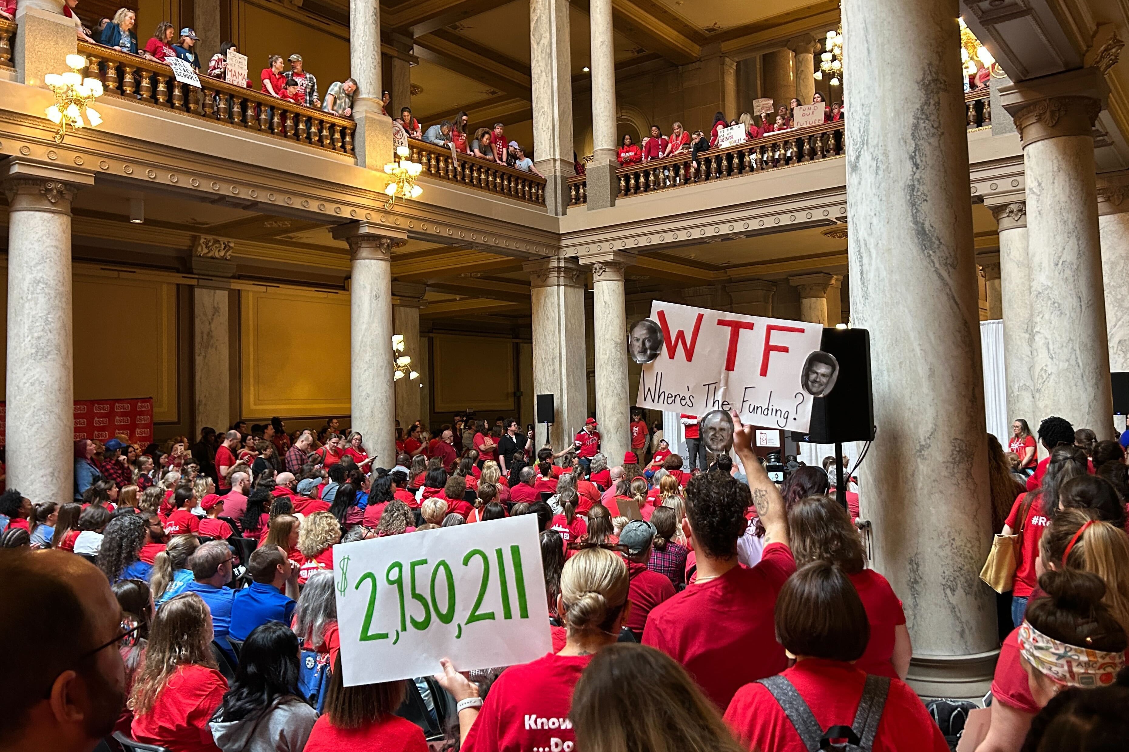 A large group of people in red t-shirts gather in a large state Capitol building.