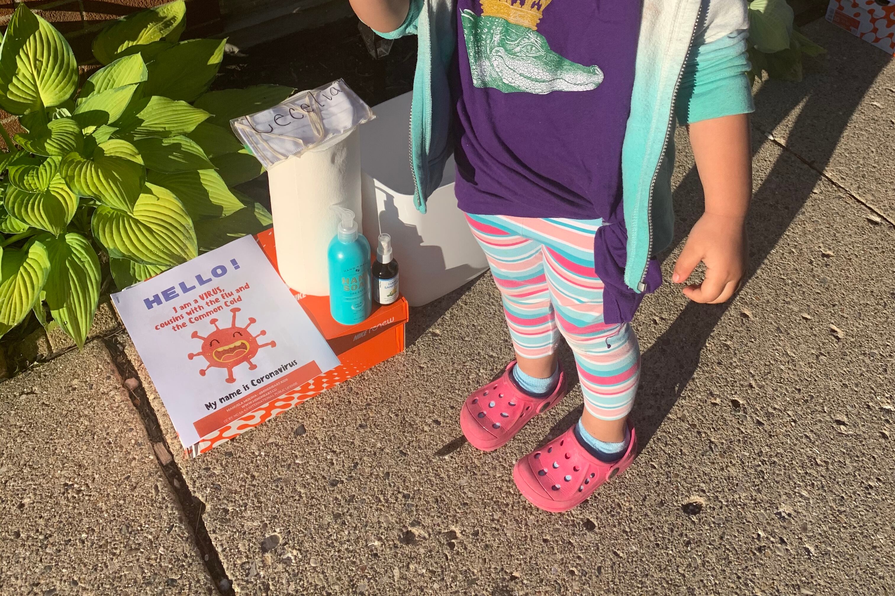 child in purple shirt stands with mask and thermometer outside of child care center in Detroit