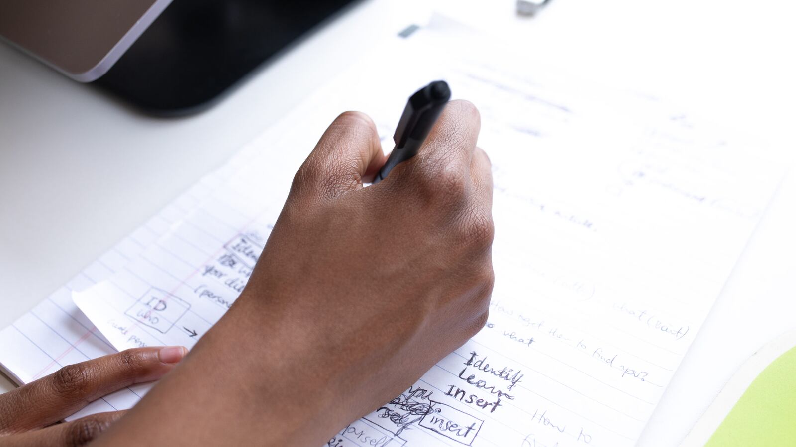 Close up of a hand writing with a pen on notebook paper.