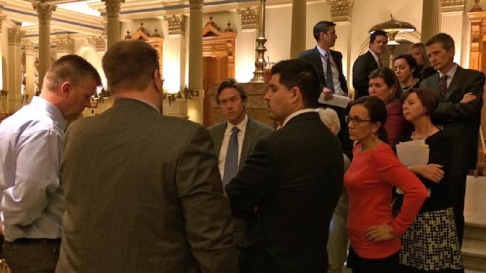 Sen. Mike Johnston (center, facing camera) talks with lobbyists and senators.