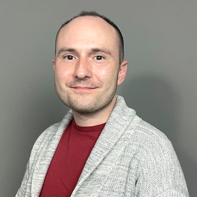 A man in a red t-shirt and gray sweater.