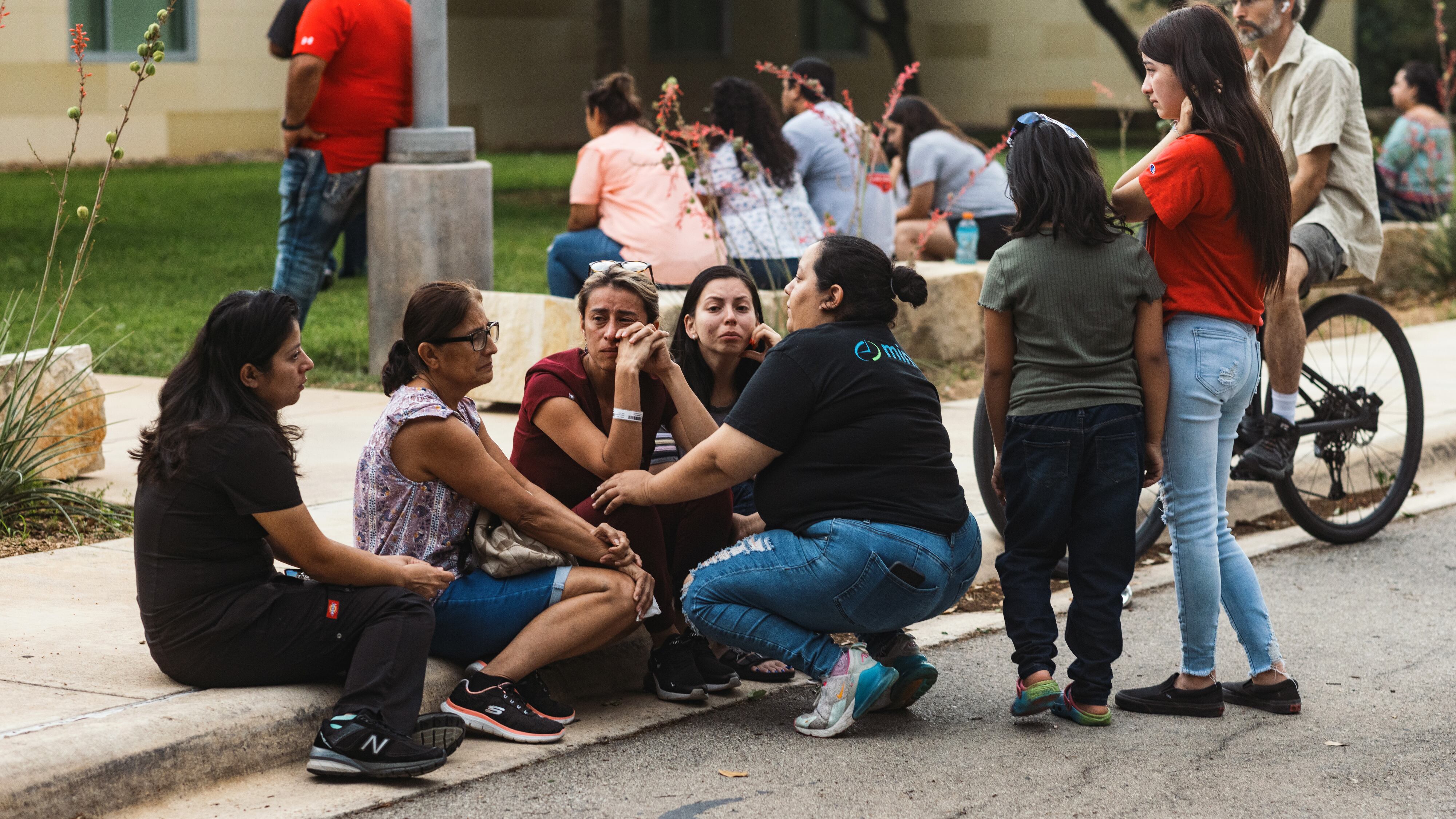 Community members grieve on a sidewalk after a mass shooting in Uvalde, Texas.