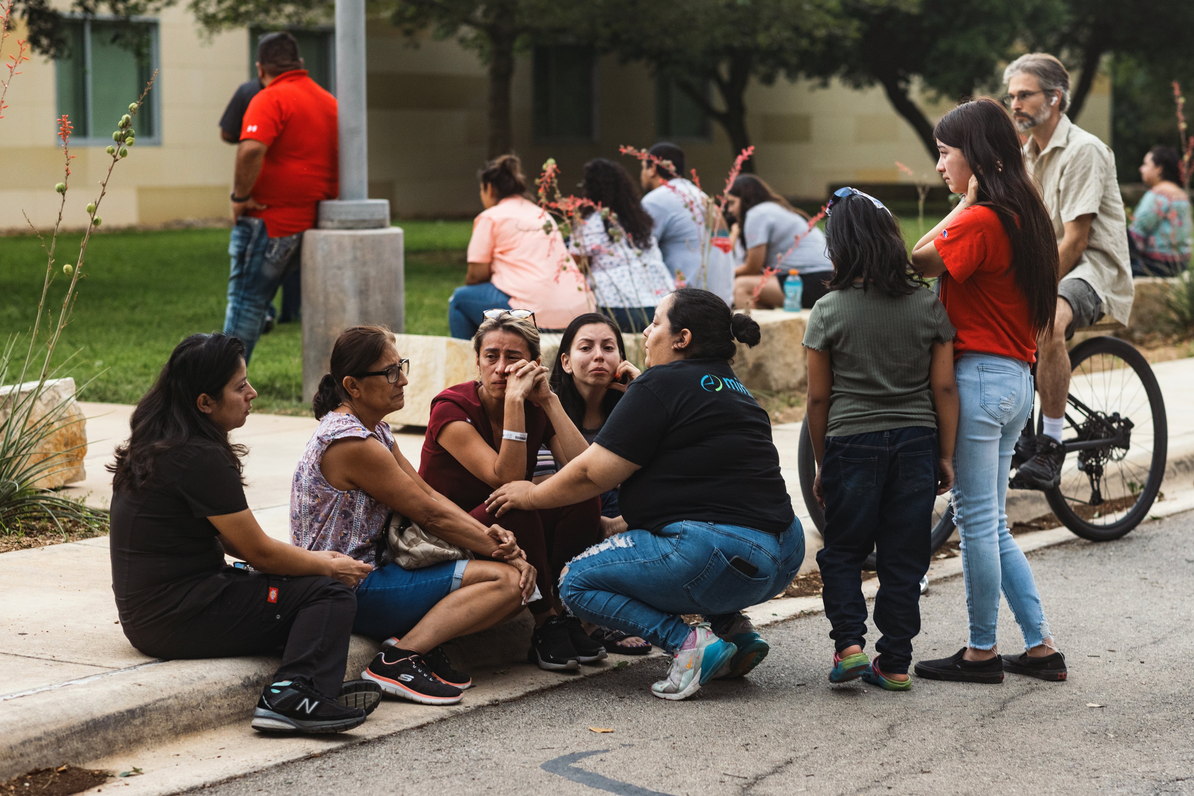 Community members grieve on a sidewalk after a mass shooting in Uvalde, Texas.