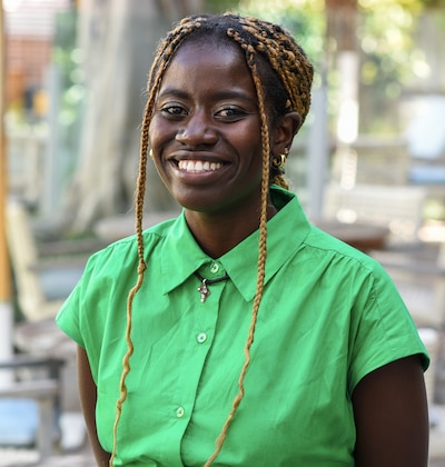 Headshot of a woman wearing a green short sleeve shirt. Her hair is in braids.