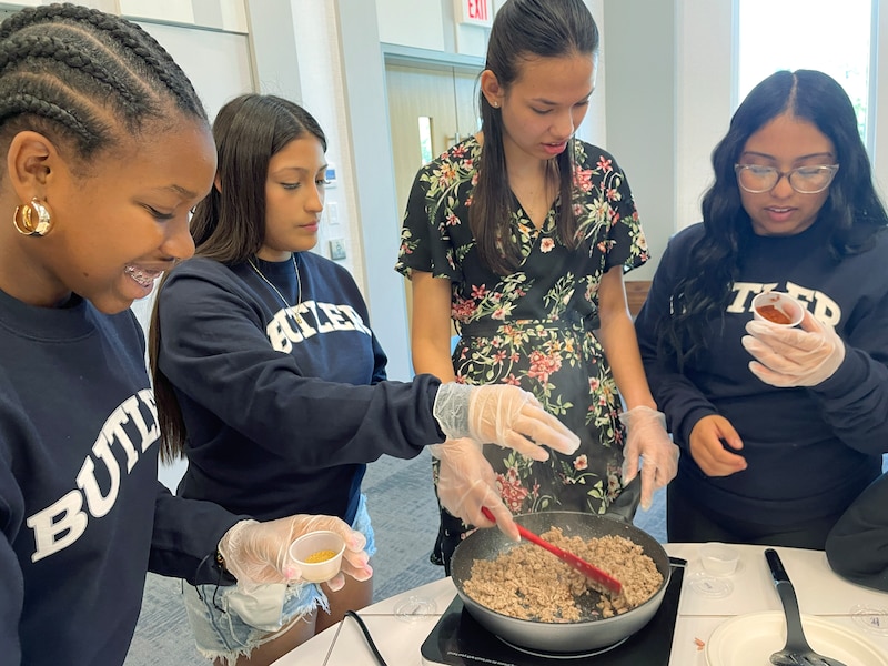 A group of students work around a pot of food