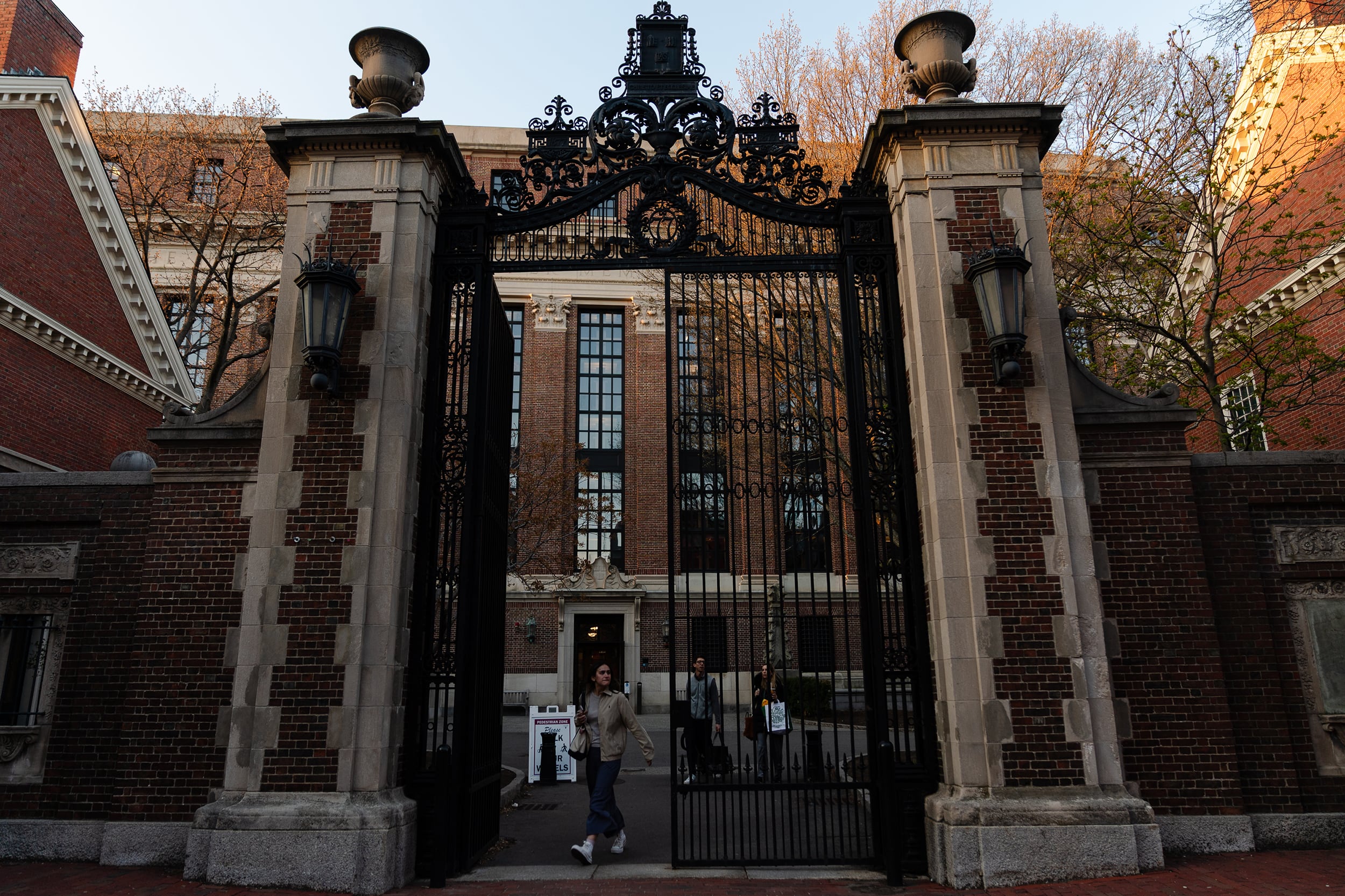 A photograph of a person leaving a giant stone building with a gated entrance.