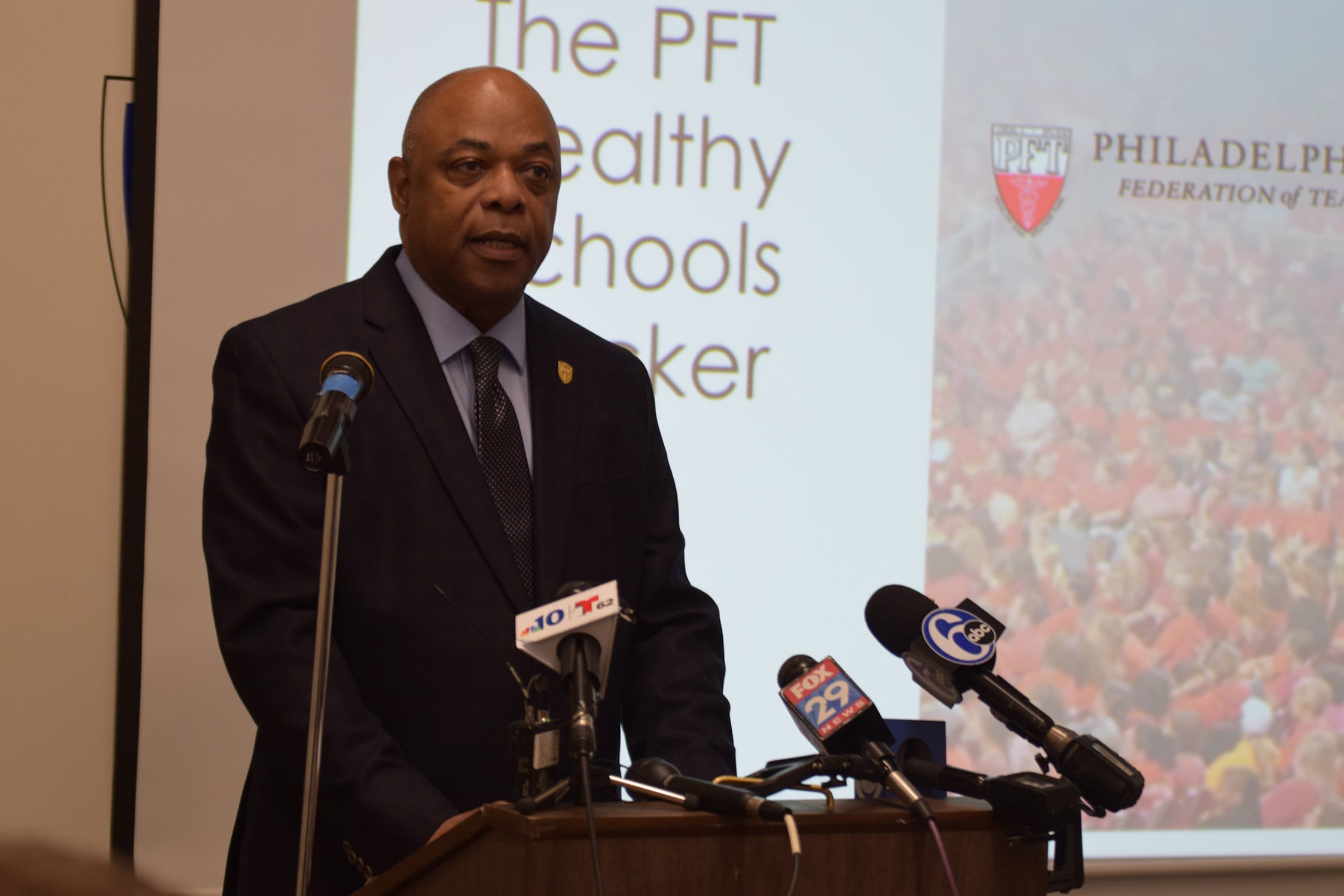 Jerry Jordan standing at a podium speaking into microphones.