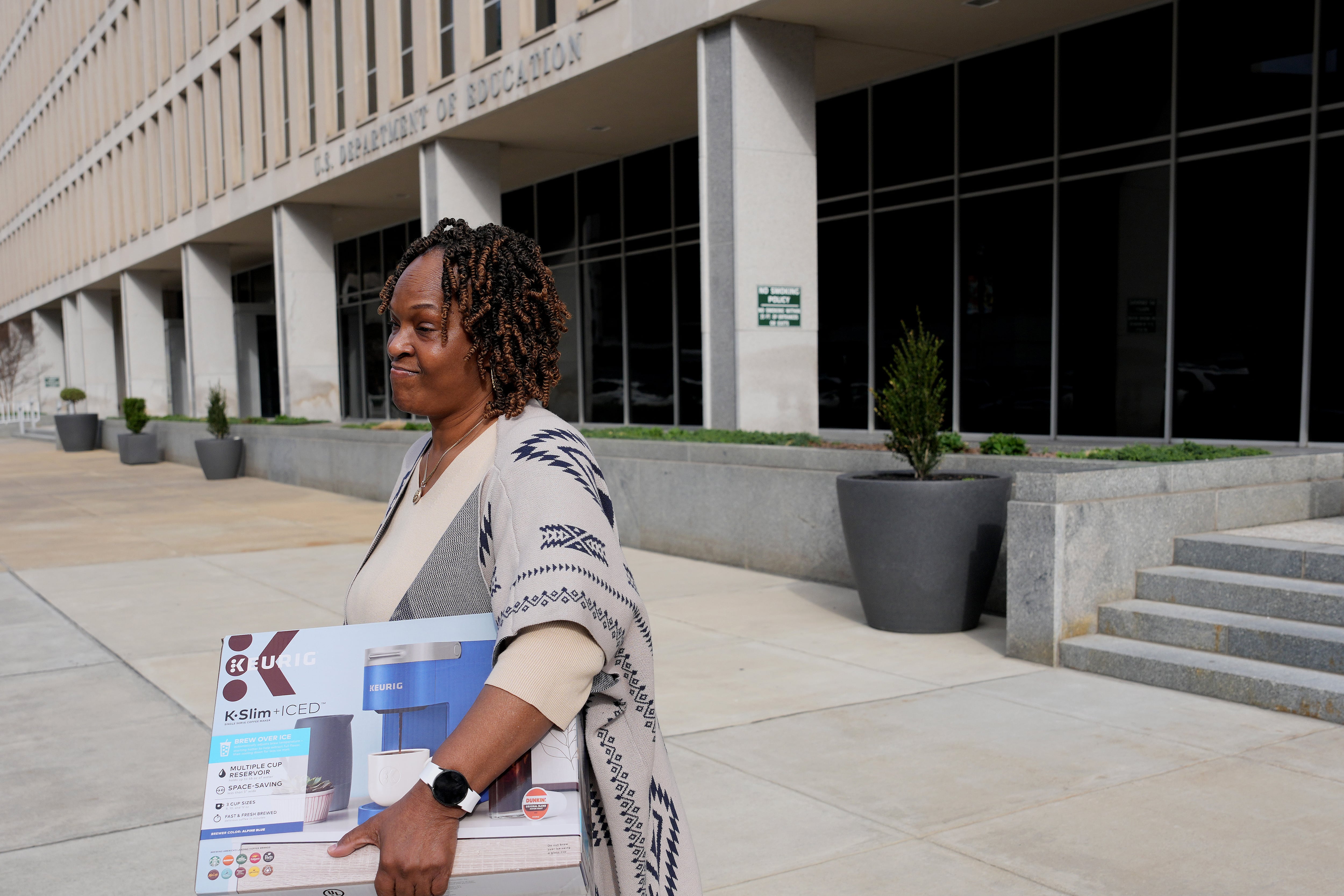 A woman carried a box out of an official-looking building.