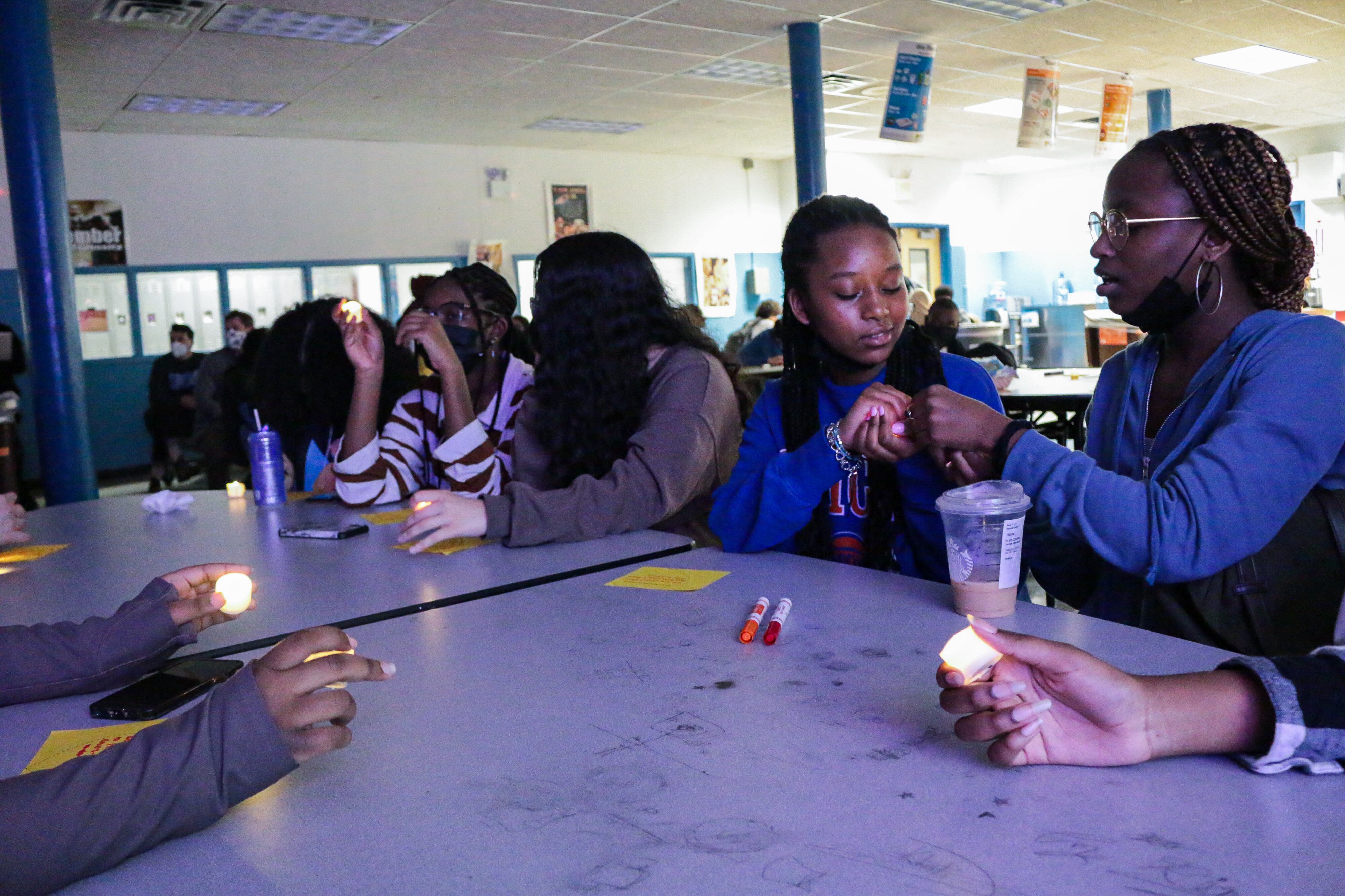 Students are in discussion with each other at a table with snacks and markers.