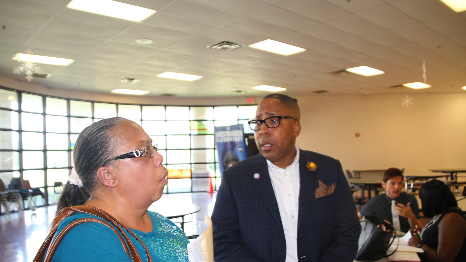 Rodney Rowan, assistant superintendent and new leader of the district's iZone, talks with his former colleague Sandra Jenkins at a job fair. Jenkins is looking for work after a car accident forced into early retirement several years ago.