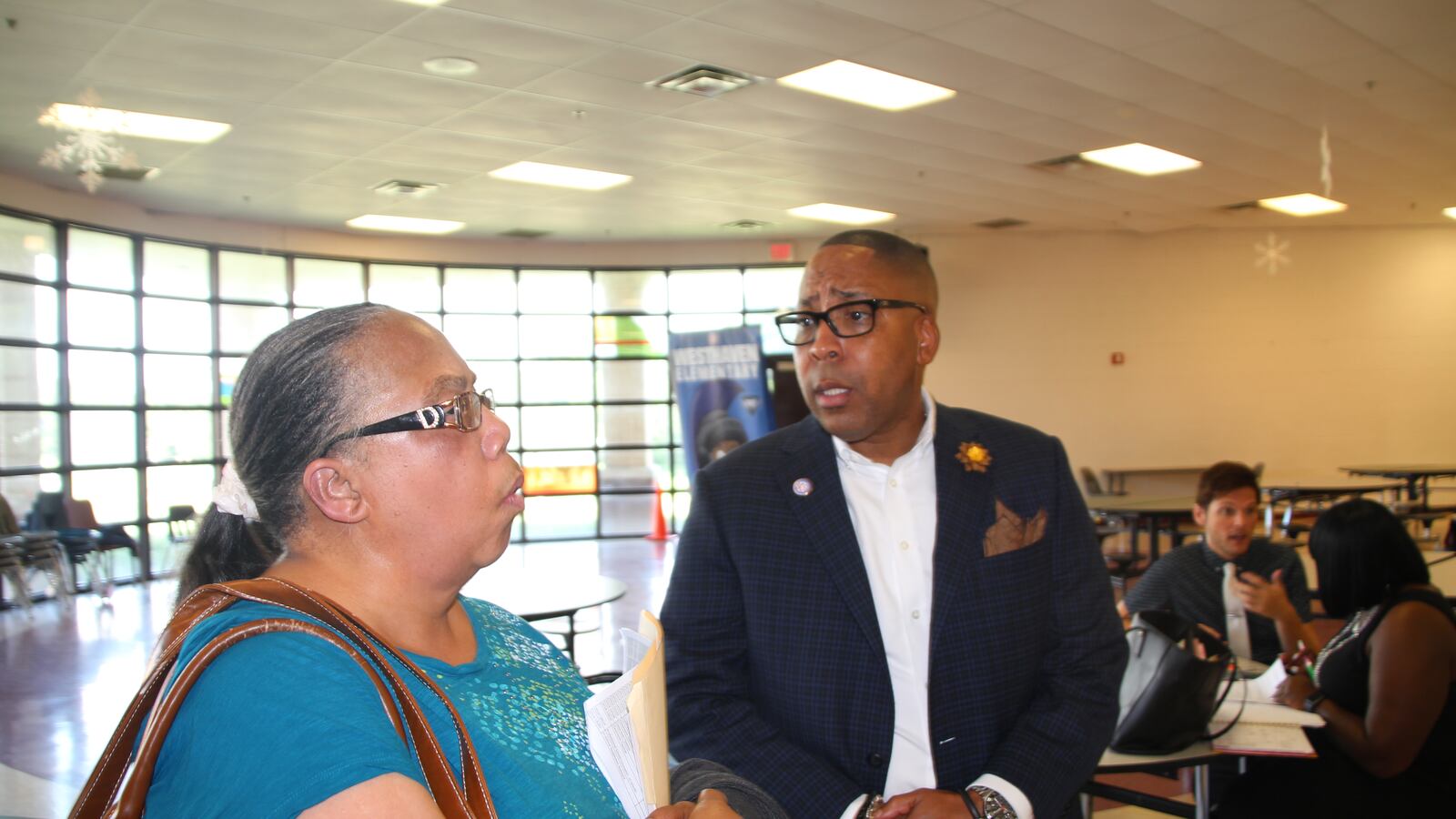 Rodney Rowan, assistant superintendent and new leader of the district's iZone, talks with his former colleague Sandra Jenkins at a job fair. Jenkins is looking for work after a car accident forced into early retirement several years ago.