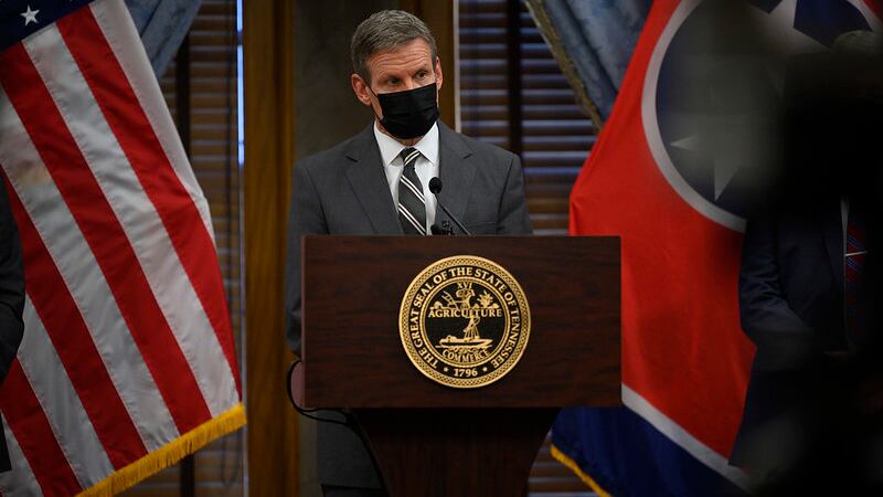 Tennessee Gov. Bill Lee stands alone and masked a podium with the U.S. flag to his left and the state flag to his right. 