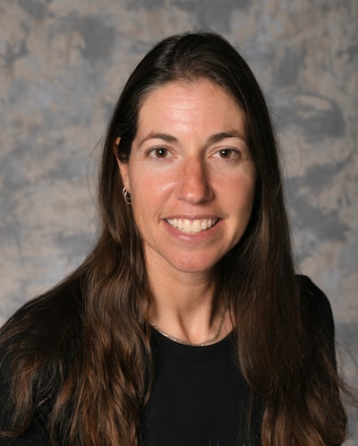 A portrait of a woman with long hair and a dark top.