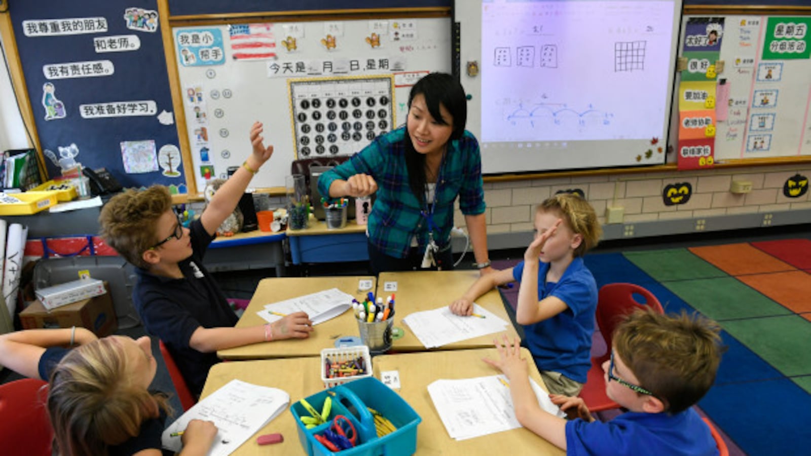 Teacher Yu-Hsin Lien helps her third-grade students with classwork at the Denver Language School, a popular K-8 charter school.