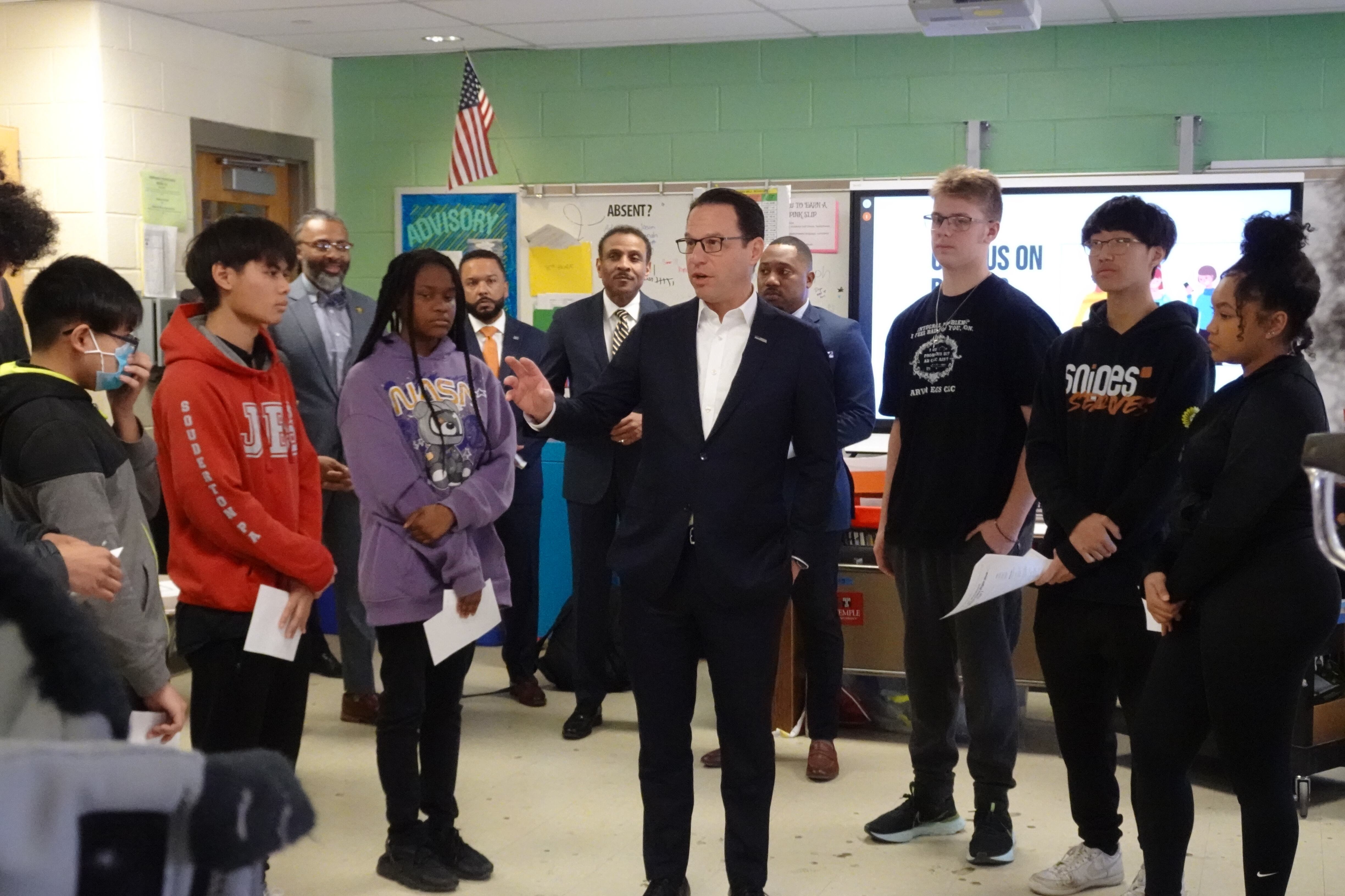 Gov. Josh Shapiro in a blue suit and white shirt talks to a group of high school students in a classroom.