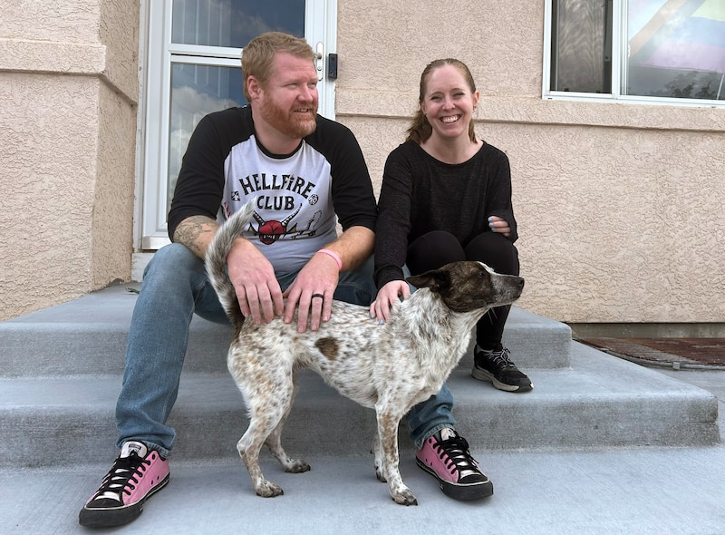 A man and a woman sit on a step with a dog,