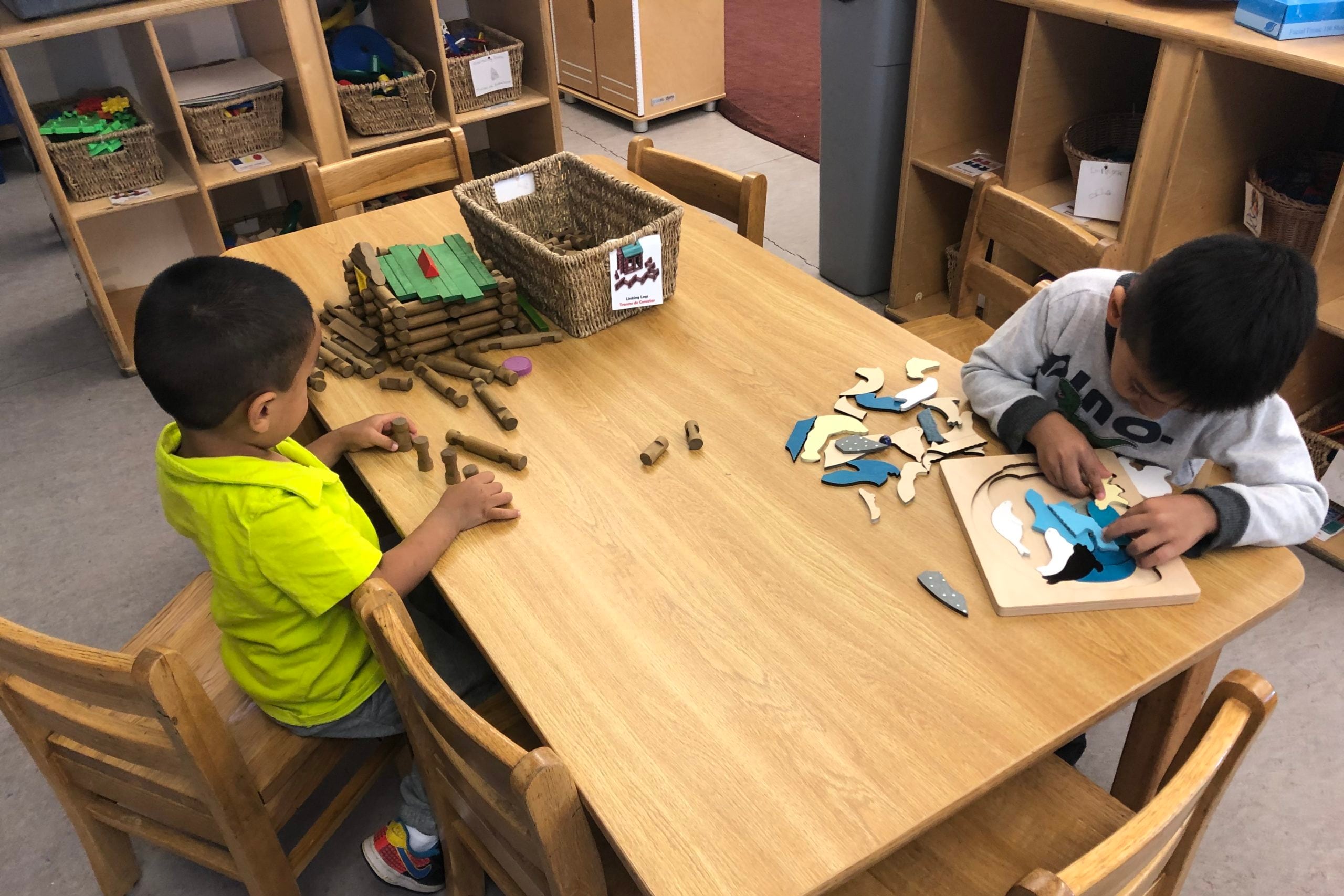 Two preschool children work at a puzzle table in Chicago.