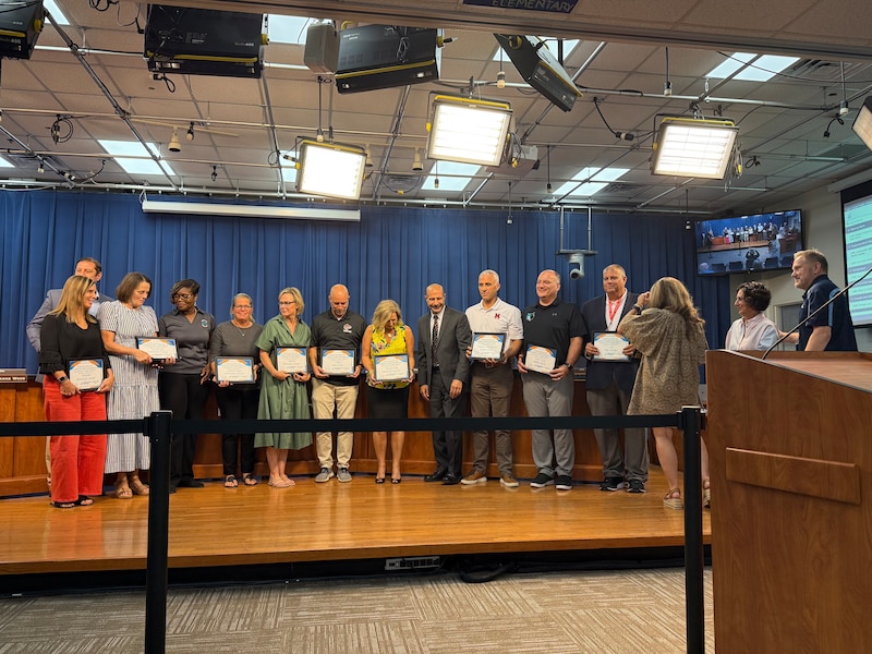 A photograph of a line of adults standing for a photograph on a stage.