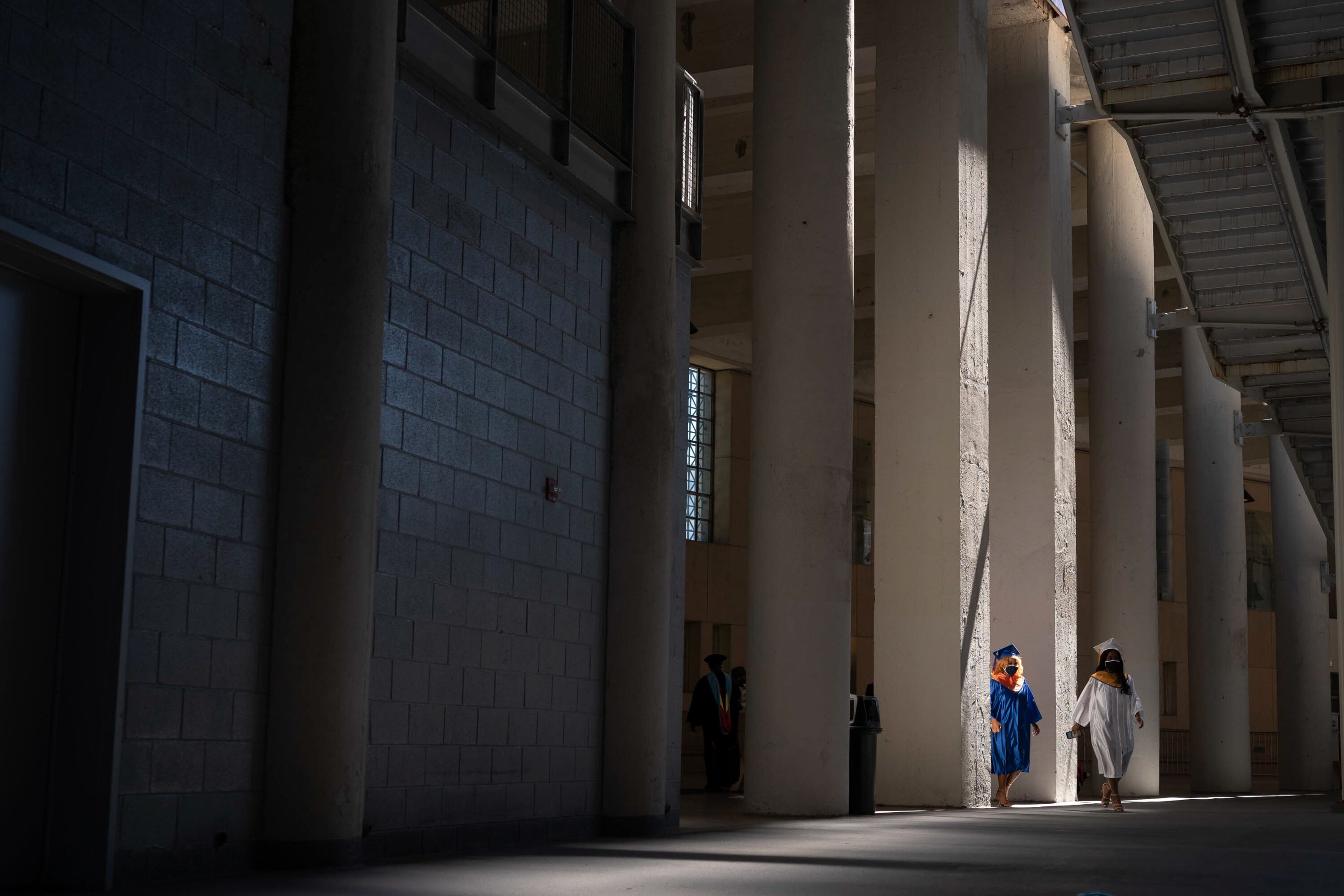 Two student in graduation gowns get in line for graduation.