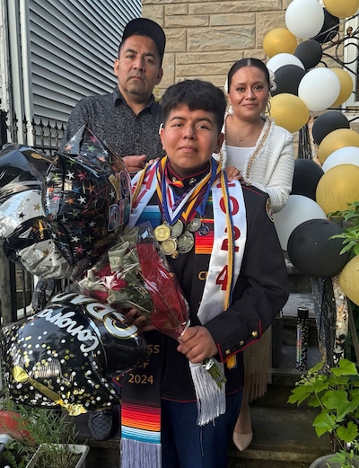 Two adults and one high school senior pose for a portrait with lots of decorations.