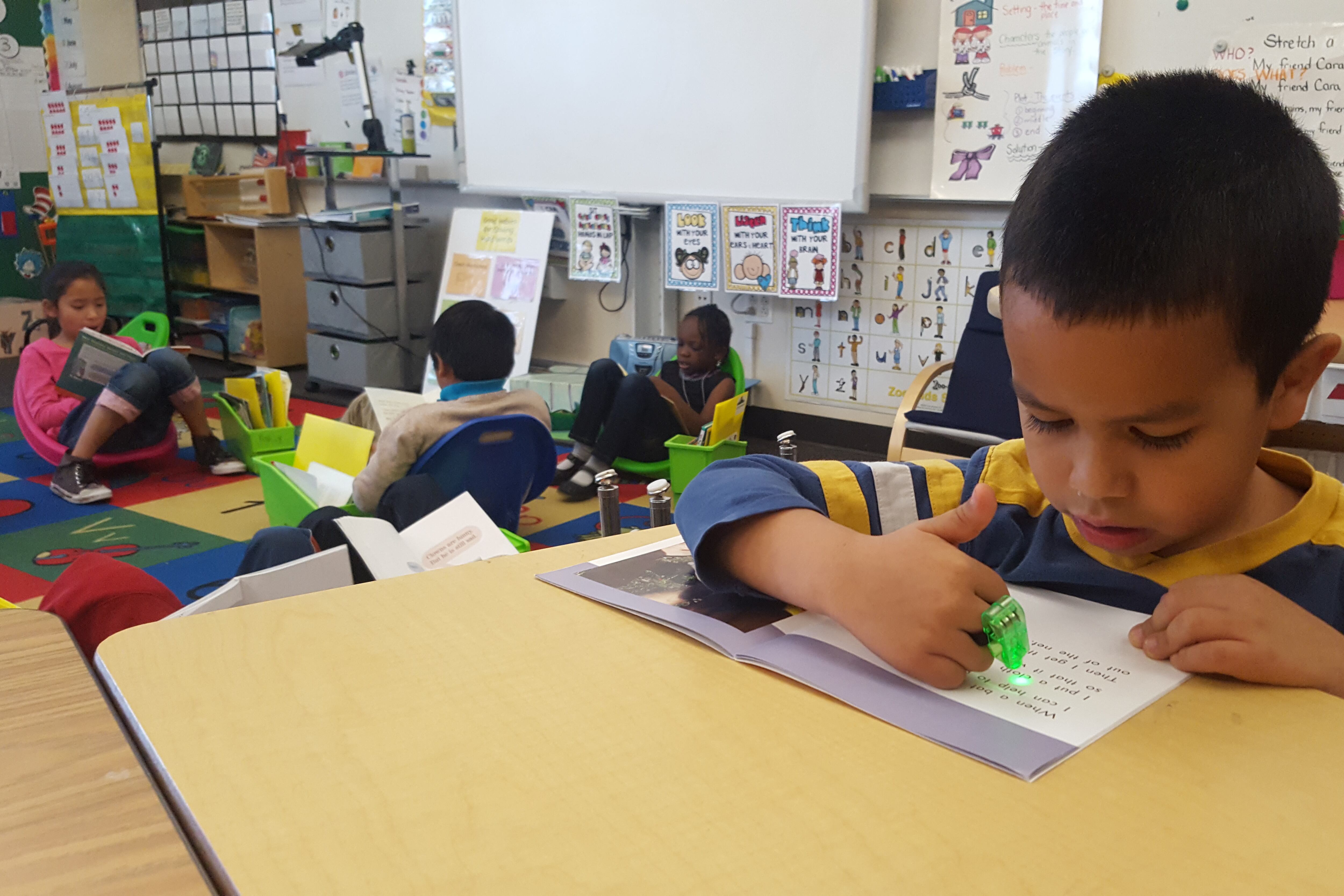 First graders at Paris Elementary in Aurora use toys and light pointers to help focus while reading individually.