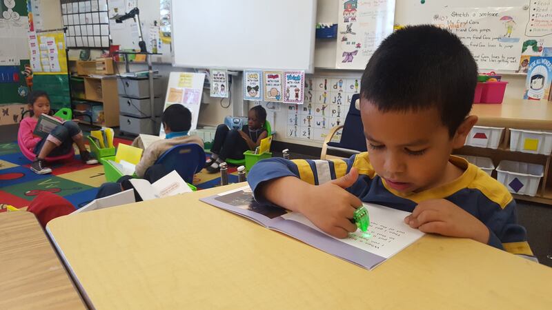 First graders at Paris Elementary in Aurora use toys and light pointers to help focus while reading individually.