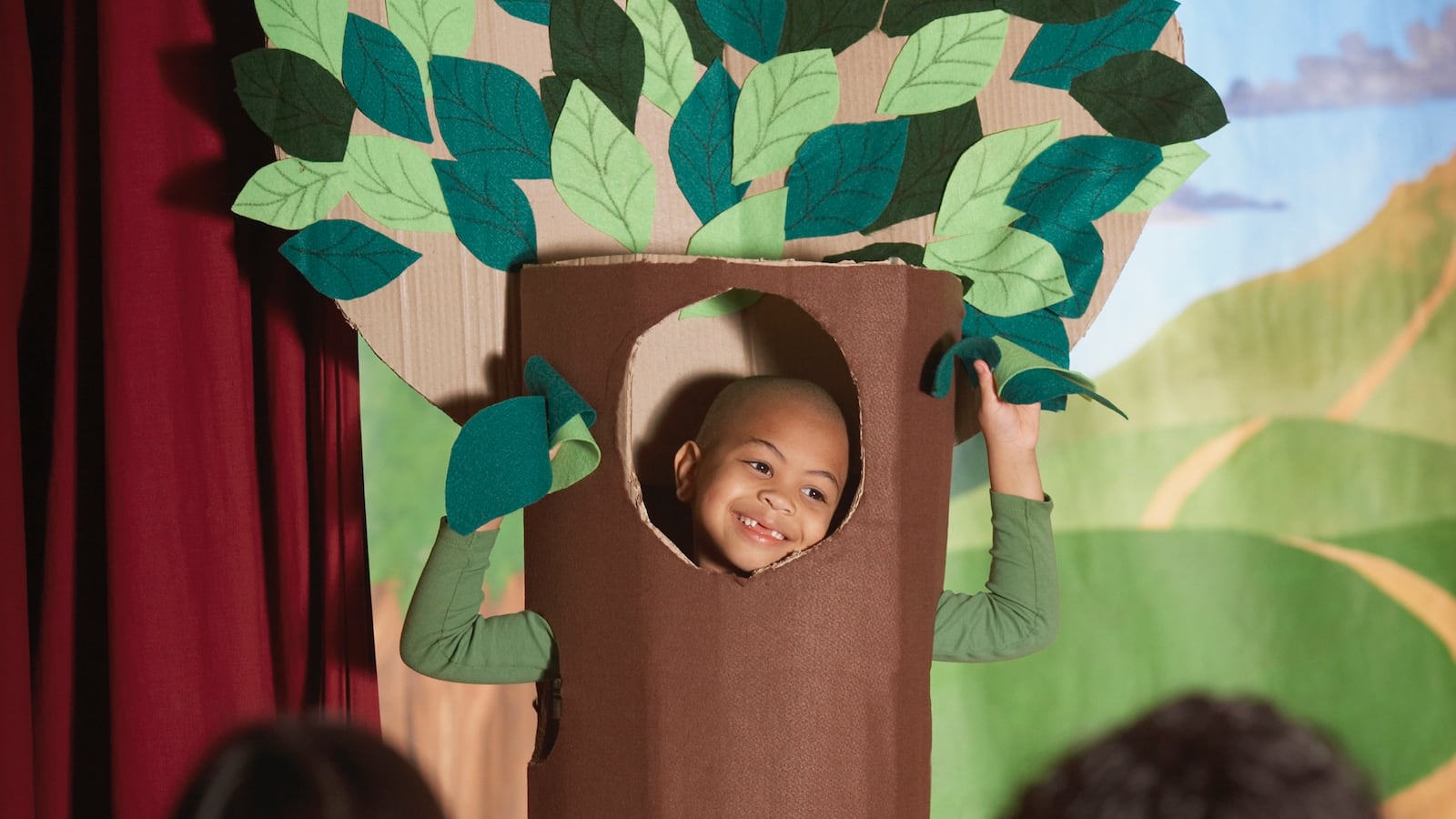 Young boy in a tree costume performs on stage. 