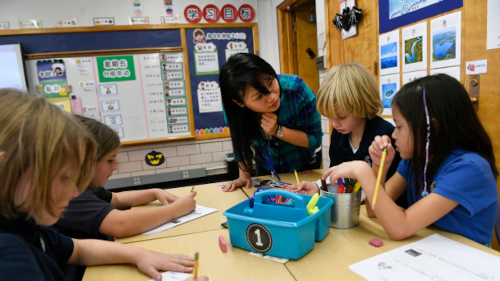 Teacher Yu-Hsin Lien helps her third-grade students with classwork at the Denver Language School.