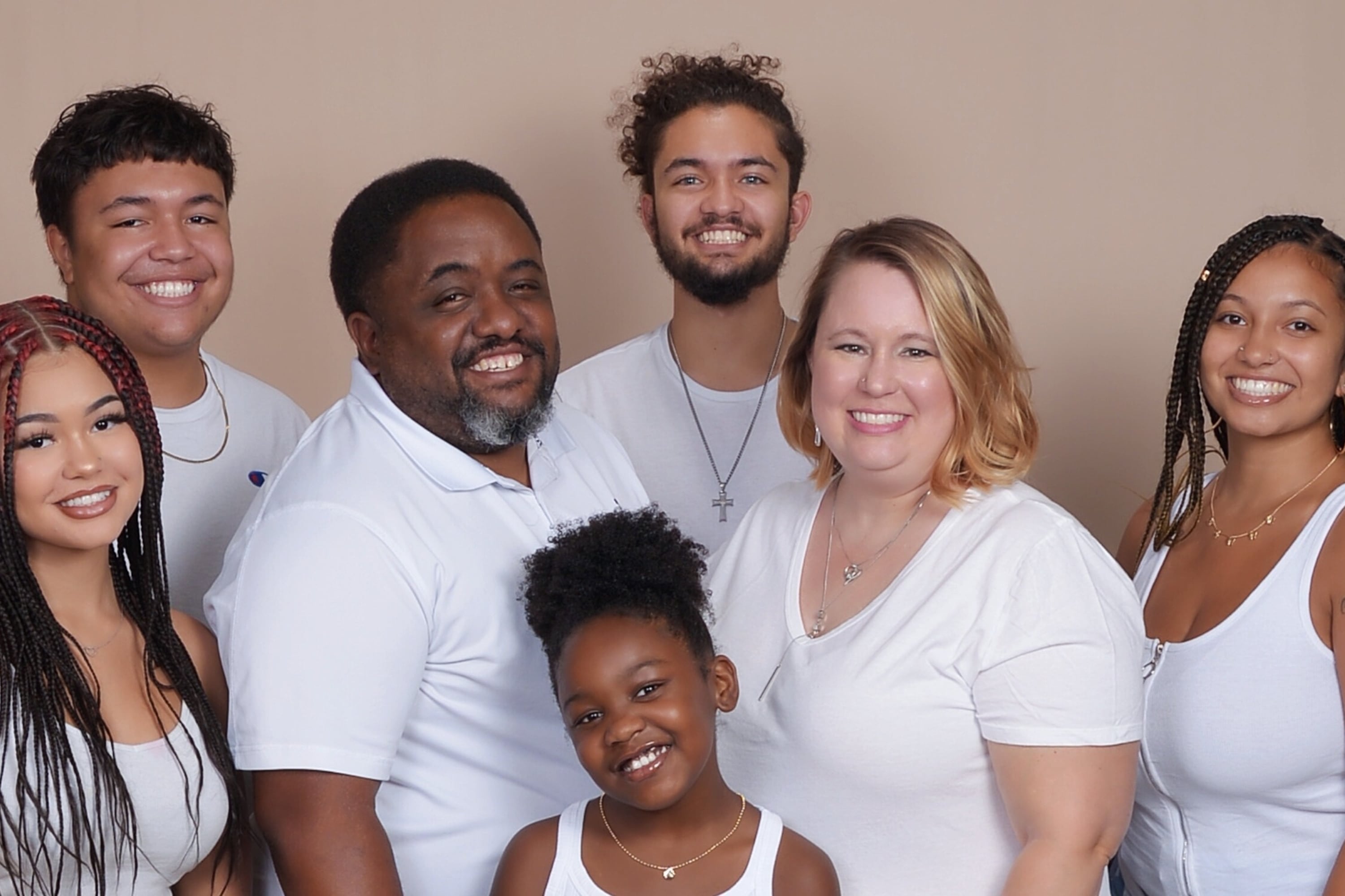 A family portrait Vernon Jones Jr., his wife, and five children. They are all wearing white shirts and smiling at the camera.